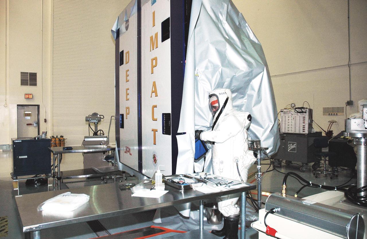 KENNEDY SPACE CENTER, FLA. -  A worker at Astrotech Space Operations in Titusville, Fla., begins fueling the Deep Impact spacecraft. Scheduled for liftoff Jan. 12,  Deep Impact will probe beneath the surface of Comet Tempel 1 on July 4, 2005, when the comet is 83 million miles from Earth, and reveal the secrets of its interior.   After releasing a 3- by 3-foot projectile to crash onto the surface, Deep Impact’s flyby spacecraft will collect pictures and data of how the  crater forms, measuring the crater’s depth and diameter, as well as the composition of the interior of the crater and any material thrown out, and determining the changes in natural outgassing produced by the impact.  It will send the data back to Earth through the antennas of the Deep Space Network.  Deep Impact is a NASA Discovery mission.