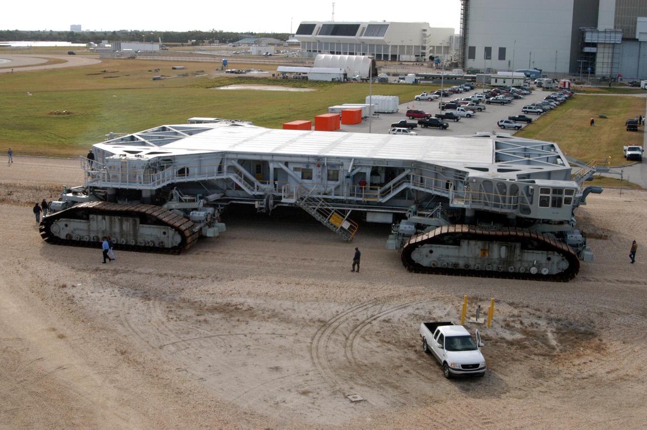 KENNEDY SPACE CENTER, FLA. - Observers walk alongside the newly shod Crawler Transporter as it moves slowly forward. The Crawler Transporter that will move Space Shuttle Discovery to the launch pad for Return to Flight is taking its first road test following the replacement of all its shoes. The crawlers have 456 shoes, 57 per belt (8 belts in all). Each shoe weighs 2,200 pounds. Cracks appeared in the shoes in recent years, spurring a need for replacement. The new manufacturer, in Duluth, Minn., has improved the design for a safe Return to Flight and use through the balance of the Space Shuttle Program.