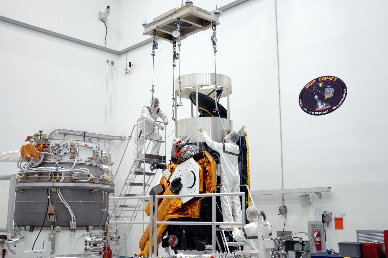 KENNEDY SPACE CENTER, FLA. - At Astrotech Space Operations in Titusville, Fla., Boeing technicians attach a crane to the Deep Impact spacecraft in order to move it to the Delta II third stage at left for mating. When the spacecraft and third stage are mated, they will be moved to Launch Pad 17-B at Cape Canaveral Air Force Station, Fla.  There they will be mated to the Delta II rocket and the fairing installed around them for protection during launch and ascent.  Scheduled for liftoff Jan. 12,  Deep Impact will probe beneath the surface of Comet Tempel 1 on July 4, 2005, when the comet is 83 million miles from Earth.  After releasing a 3- by 3-foot projectile to crash onto the surface, Deep Impact’s flyby spacecraft will reveal the secrets of its interior by collecting pictures and data of how the crater forms, measuring the crater’s depth and diameter as well as the composition of the interior of the crater and any material thrown out, and determining the changes in natural outgassing produced by the impact.  It will send the data back to Earth through the antennas of the Deep Space Network.  Deep Impact is a NASA Discovery mission.