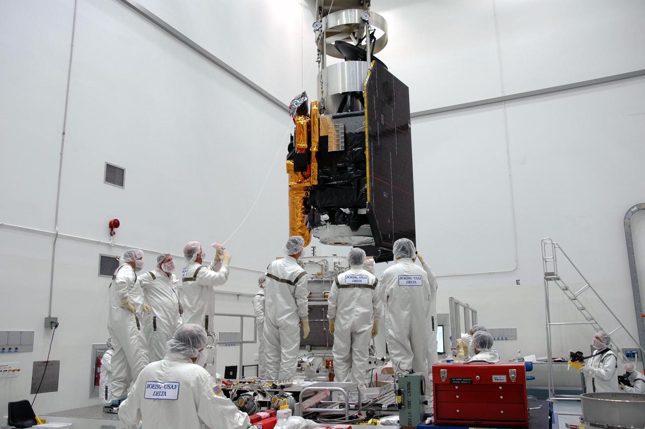 KENNEDY SPACE CENTER, FLA. - At Astrotech Space Operations in Titusville, Fla., Boeing technicians watch as an overhead crane lowers the Deep Impact spacecraft onto the Delta II third stage for mating. When the spacecraft and third stage are mated, they will be moved to Launch Pad 17-B at Cape Canaveral Air Force Station, Fla.  There they will be mated to the Delta II rocket and the fairing installed around them for protection during launch and ascent.  Scheduled for liftoff Jan. 12,  Deep Impact will probe beneath the surface of Comet Tempel 1 on July 4, 2005, when the comet is 83 million miles from Earth.  After releasing a 3- by 3-foot projectile to crash onto the surface, Deep Impact’s flyby spacecraft will reveal the secrets of its interior by collecting pictures and data of how the crater forms, measuring the crater’s depth and diameter as well as the composition of the interior of the crater and any material thrown out, and determining the changes in natural outgassing produced by the impact.  It will send the data back to Earth through the antennas of the Deep Space Network.  Deep Impact is a NASA Discovery mission.
