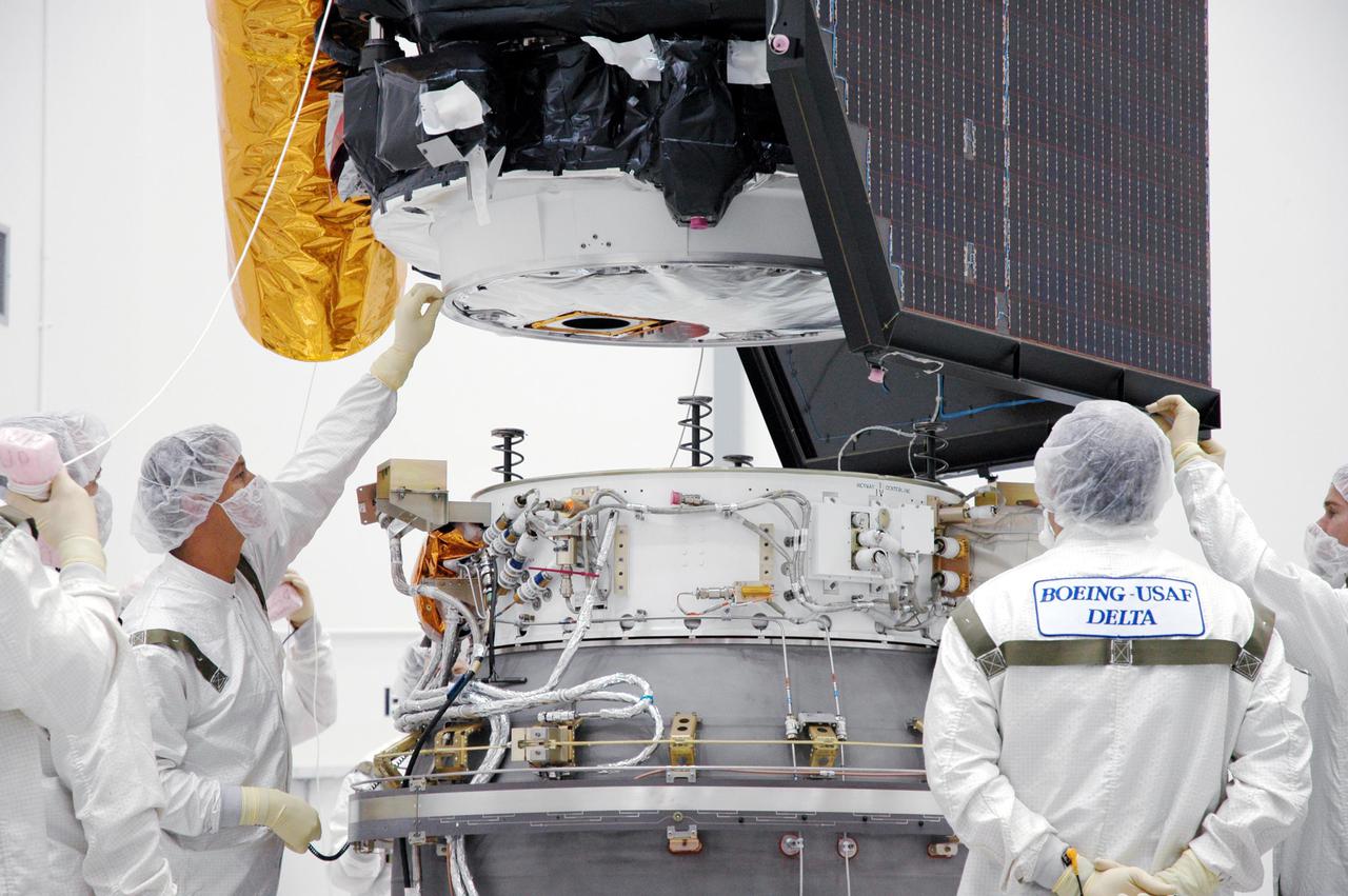 KENNEDY SPACE CENTER, FLA. - At Astrotech Space Operations in Titusville, Fla., Boeing technicians oversee the final movement of the Deep Impact spacecraft being lowered onto the Delta II third stage for mating. When the spacecraft and third stage are mated, they will be moved to Launch Pad 17-B at Cape Canaveral Air Force Station, Fla.  There they will be mated to the Delta II rocket and the fairing installed around them for protection during launch and ascent.  Scheduled for liftoff Jan. 12,  Deep Impact will probe beneath the surface of Comet Tempel 1 on July 4, 2005, when the comet is 83 million miles from Earth.  After releasing a 3- by 3-foot projectile to crash onto the surface, Deep Impact’s flyby spacecraft will reveal the secrets of its interior by collecting pictures and data of how the crater forms, measuring the crater’s depth and diameter as well as the composition of the interior of the crater and any material thrown out, and determining the changes in natural outgassing produced by the impact.  It will send the data back to Earth through the antennas of the Deep Space Network.  Deep Impact is a NASA Discovery mission.