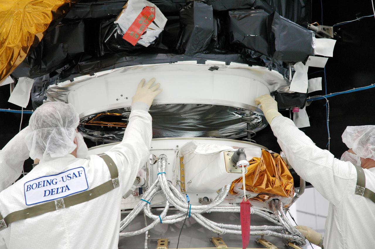 KENNEDY SPACE CENTER, FLA. - At Astrotech Space Operations in Titusville, Fla., Boeing technicians oversee the final movement of the Deep Impact spacecraft being lowered onto the Delta II third stage for mating. When the spacecraft and third stage are mated, they will be moved to Launch Pad 17-B at Cape Canaveral Air Force Station, Fla.  There they will be mated to the Delta II rocket and the fairing installed around them for protection during launch and ascent.  Scheduled for liftoff Jan. 12,  Deep Impact will probe beneath the surface of Comet Tempel 1 on July 4, 2005, when the comet is 83 million miles from Earth.  After releasing a 3- by 3-foot projectile to crash onto the surface, Deep Impact’s flyby spacecraft will reveal the secrets of its interior by collecting pictures and data of how the crater forms, measuring the crater’s depth and diameter as well as the composition of the interior of the crater and any material thrown out, and determining the changes in natural outgassing produced by the impact.  It will send the data back to Earth through the antennas of the Deep Space Network.  Deep Impact is a NASA Discovery mission.