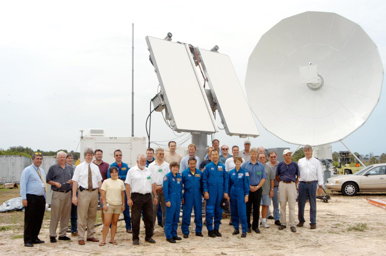 KENNEDY SPACE CENTER, FLA.  - Members of the STS-114 crew pose for a photo with workers installing the 30-foot-diameter C-band antenna and a smaller X-band antenna (behind them) north of the Haulover Canal.  The astronauts are Mission Specialist Stephen Robinson and Pilot James Kelly, in the back row at left; and in front, Mission Specialists Wendy Lawrence, Charles Camarda and Soichi Noguchi, and Commander Eileen Collins. The antennas are being tested during the launch of a Delta II rocket carrying NASA’s MESSENGER spacecraft bound for the planet Mercury that will work together to create an image of the Delta rocket in flight. The test will evaluate the use of the radars as part of NASA’s Return to Flight program for the Space Shuttle to observe possible debris coming from the Shuttle during launch.  If successful, the radar configuration could be used on ships downrange, including on one of the solid rocket booster retrieval ships.  And it may enable the return to launching Space Shuttles at night.  The launch window for Return to Flight mission STS-114 is May 12 through June 3, 2005.
