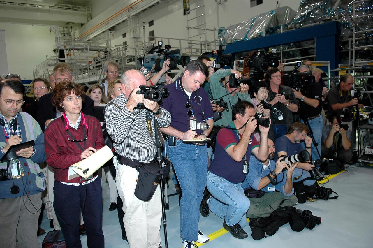 KENNEDY SPACE CENTER, FLA. - Photographers and journalists gather in the Space Station Processing Facility (SSPF) to interview and photograph the STS-114 crew, who are looking over some of the hardware in the SSPF. The crew is at KSC for Crew Equipment Interface Test (CEIT) activities. During CEIT, the crew has an opportunity to get a hands-on look at the payloads with which they’ll be working on-orbit. The Return to Flight mission STS-114 will carry the Multi-Purpose Logistics Module Raffaello, filled with supplies for the International Space Station, and a replacement Control Moment Gyroscope. Launch of STS-114 has a launch window of May 12 to June 3.