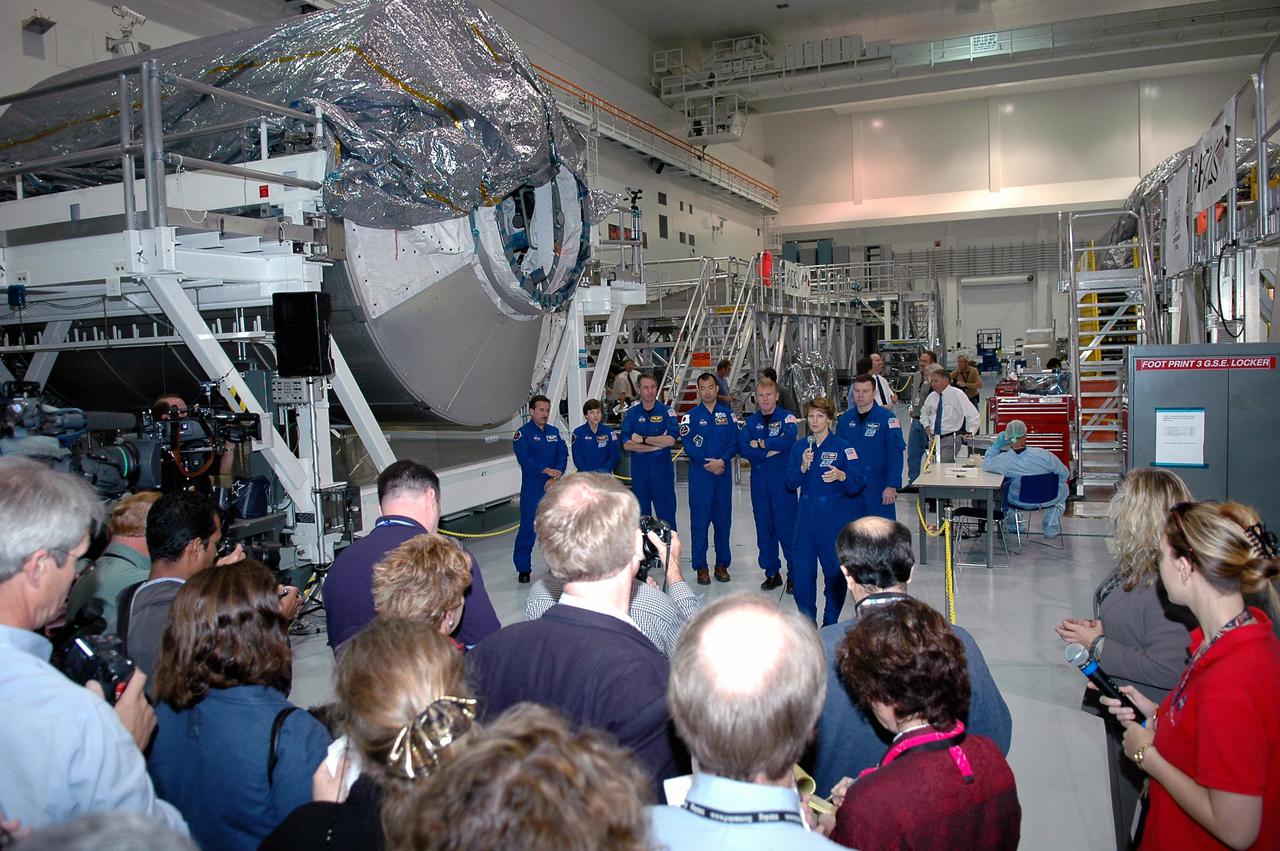 KENNEDY SPACE CENTER, FLA. - Photographers and journalists gather in the Space Station Processing Facility (SSPF) to interview and photograph the STS-114 crew. Crew members from left are ) Mission Specialists Charles Camarda, Wendy Lawrence, Stephen Robinson, Soichi Noguchi (with the Japanese Space Agency) and Andrew Thomas; Commander Eileen Collins; and Pilot James Kelly. The crew is looking over some of the hardware in the SSPF. The crew is at KSC for Crew Equipment Interface Test (CEIT) activities. During CEIT, the crew has an opportunity to get a hands-on look at the payloads with which they’ll be working on-orbit. The Return to Flight mission STS-114 will carry the Multi-Purpose Logistics Module Raffaello, filled with supplies for the International Space Station, and a replacement Control Moment Gyroscope. Launch of STS-114 has a launch window of May 12 to June 3.