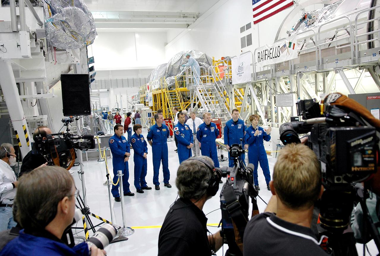 KENNEDY SPACE CENTER, FLA. - Photographers and journalists gather in the Space Station Processing Facility (SSPF) to interview and photograph the STS-114 crew. Crew members from left are ) Mission Specialists Charles Camarda, Wendy Lawrence, Stephen Robinson, Soichi Noguchi (with the Japanese Space Agency) and Andrew Thomas; Pilot James Kelly; and Commander Eileen Collins. The crew is looking over some of the hardware in the SSPF. The Multi-Purpose Logistics Module Raffaello that will fly on mission STS-114 is at right. The crew is at KSC for Crew Equipment Interface Test (CEIT) activities. During CEIT, the crew has an opportunity to get a hands-on look at the payloads with which they’ll be working on-orbit. The Return to Flight mission STS-114 will also carry a replacement Control Moment Gyroscope. Launch of STS-114 has a launch window of May 12 to June 3.