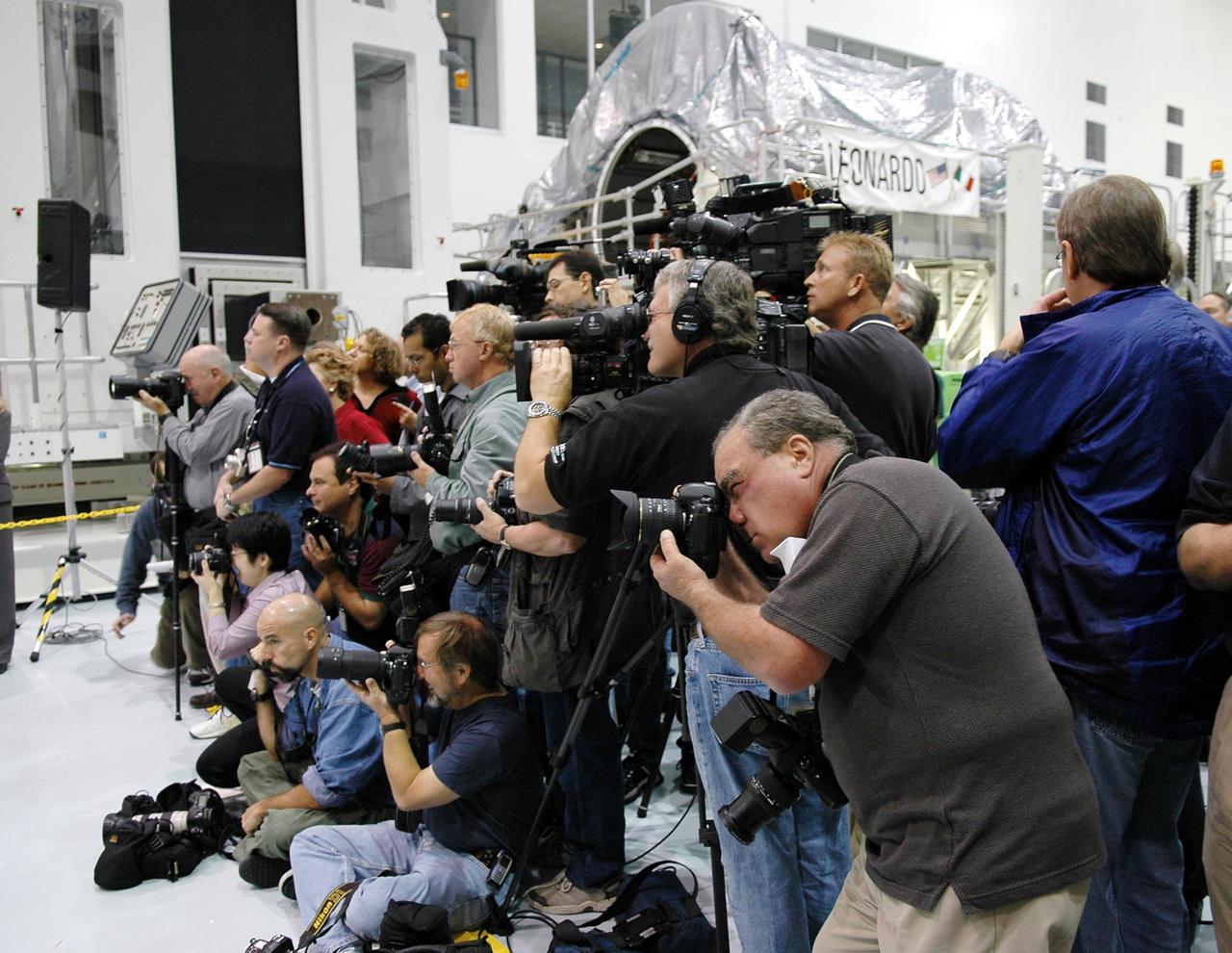 KENNEDY SPACE CENTER, FLA. - Photographers and journalists gather in the Space Station Processing Facility (SSPF) to interview and photograph the STS-114 crew. The crew is looking over some of the hardware in the SSPF. Behind the photographers is the Multi-Purpose Logistics Module Leonardo. STS-114 will carry its sister module Raffaello. The crew is at KSC for Crew Equipment Interface Test (CEIT) activities. During CEIT, the crew has an opportunity to get a hands-on look at the payloads with which they’ll be working on-orbit. The Return to Flight mission STS-114 will also carry a replacement Control Moment Gyroscope. Launch of STS-114 has a launch window of May 12 to June 3.