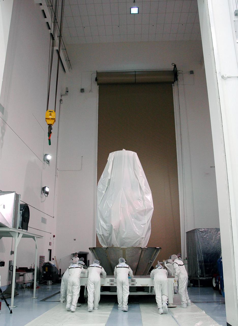 KENNEDY SPACE CENTER, FLA. - At Astrotech Space Operations in Titusville, Fla., Boeing technicians roll the Deep Impact spacecraft into another area where the upper canister can be lowered around it. Once the spacecraft is completely covered, it will be transferred to Launch Pad 17-B on Cape Canaveral Air Force Station, Fla.  Then, in the mobile service tower, the fairing will be installed around the spacecraft.  The fairing is a molded structure that fits flush with the outside surface of the Delta II upper stage booster and forms an aerodynamically smooth joint, protecting the spacecraft during launch.  Scheduled for liftoff Jan. 12,  Deep Impact will probe beneath the surface of Comet Tempel 1 on July 4, 2005, when the comet is 83 million miles from Earth.  After releasing a 3- by 3-foot projectile to crash onto the surface, Deep Impact’s flyby spacecraft will reveal the secrets of its interior by collecting pictures and data of how the crater forms, measuring the crater’s depth and diameter as well as the composition of the interior of the crater and any material thrown out, and determining the changes in natural outgassing produced by the impact.  It will send the data back to Earth through the antennas of the Deep Space Network.  Deep Impact is a NASA Discovery mission.