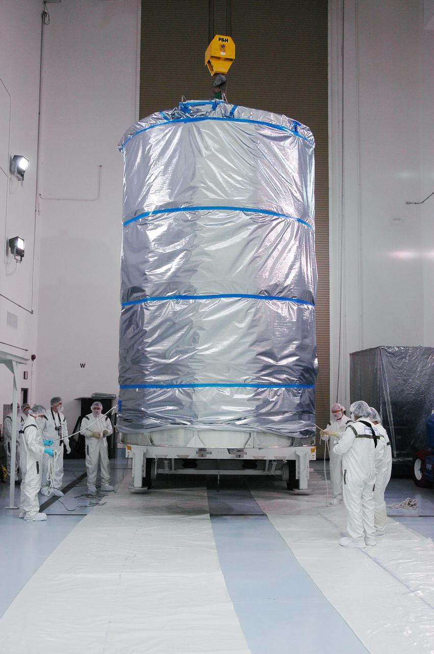 KENNEDY SPACE CENTER, FLA. - At Astrotech Space Operations in Titusville, Fla., technicians install a crane onto the upper canister before lifting it to install around the Deep Impact spacecraft.  Once the spacecraft is completely covered, it will be transferred to Launch Pad 17-B on Cape Canaveral Air Force Station, Fla.  Then, in the mobile service tower, the fairing will be installed around the spacecraft.  The fairing is a molded structure that fits flush with the outside surface of the Delta II upper stage booster and forms an aerodynamically smooth joint, protecting the spacecraft during launch.  Scheduled for liftoff Jan. 12,  Deep Impact will probe beneath the surface of Comet Tempel 1 on July 4, 2005, when the comet is 83 million miles from Earth.  After releasing a 3- by 3-foot projectile to crash onto the surface, Deep Impact’s flyby spacecraft will reveal the secrets of its interior by collecting pictures and data of how the crater forms, measuring the crater’s depth and diameter as well as the composition of the interior of the crater and any material thrown out, and determining the changes in natural outgassing produced by the impact.  It will send the data back to Earth through the antennas of the Deep Space Network.  Deep Impact is a NASA Discovery mission.