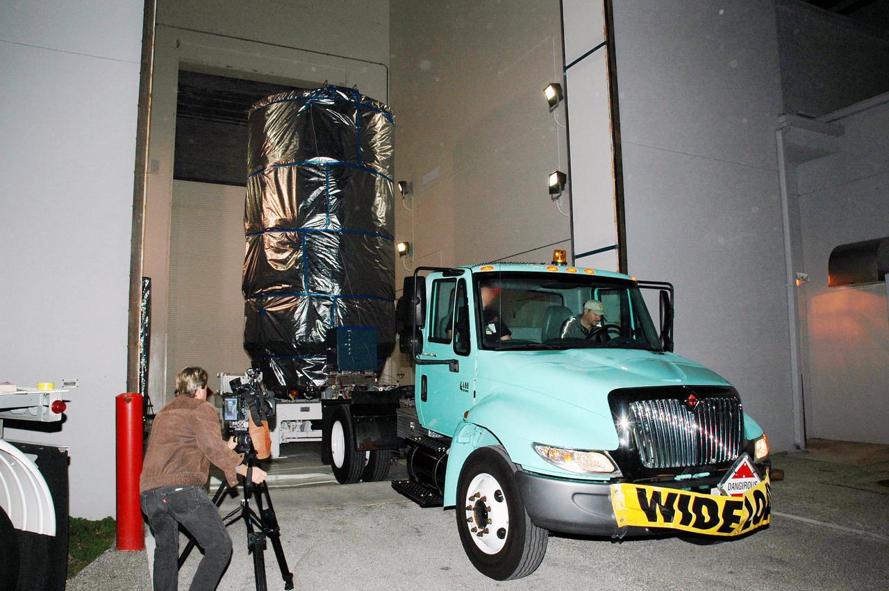 KENNEDY SPACE CENTER, FLA. - The Deep Impact spacecraft leaves Astrotech Space Operations in Titusville, Fla., in the pre-dawn hours on a journey to Launch Pad 17-B at Cape Canaveral Air Force Station, Fla.  There the spacecraft will be attached to the second stage of the Boeing Delta II rocket.  Next the fairing will be installed around the spacecraft.  The fairing is a molded structure that fits flush with the outside surface of the Delta II upper stage booster and forms an aerodynamically smooth joint, protecting the spacecraft during launch and ascent.  Scheduled for liftoff Jan. 12,  Deep Impact will probe beneath the surface of Comet Tempel 1 on July 4, 2005, when the comet is 83 million miles from Earth.  After releasing a 3- by 3-foot projectile to crash onto the surface, Deep Impact’s flyby spacecraft will reveal the secrets of its interior by collecting pictures and data of how the crater forms, measuring the crater’s depth and diameter as well as the composition of the interior of the crater and any material thrown out, and determining the changes in natural outgassing produced by the impact.  It will send the data back to Earth through the antennas of the Deep Space Network.  Deep Impact is a NASA Discovery mission.