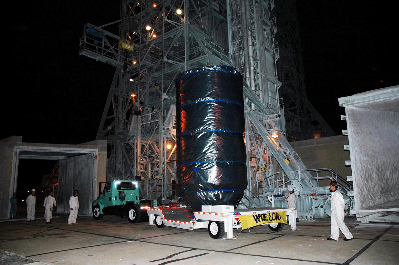 KENNEDY SPACE CENTER, FLA. - The Deep Impact spacecraft arrives before dawn at the mobile service tower on Launch Pad 17-B at Cape Canaveral Air Force Station, Fla.  The spacecraft will be attached to the second stage of the Boeing Delta II rocket.  Next the fairing will be installed around the spacecraft.  The fairing is a molded structure that fits flush with the outside surface of the Delta II upper stage booster and forms an aerodynamically smooth joint, protecting the spacecraft during launch and ascent.  Scheduled for liftoff Jan. 12,  Deep Impact will probe beneath the surface of Comet Tempel 1 on July 4, 2005, when the comet is 83 million miles from Earth.  After releasing a 3- by 3-foot projectile to crash onto the surface, Deep Impact’s flyby spacecraft will reveal the secrets of its interior by collecting pictures and data of how the crater forms, measuring the crater’s depth and diameter as well as the composition of the interior of the crater and any material thrown out, and determining the changes in natural outgassing produced by the impact.  It will send the data back to Earth through the antennas of the Deep Space Network.  Deep Impact is a NASA Discovery mission.