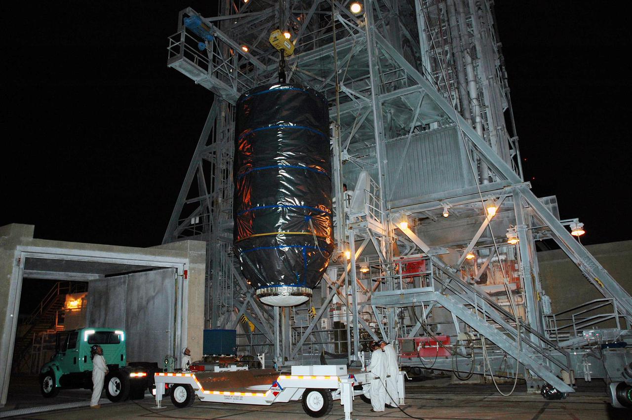 KENNEDY SPACE CENTER, FLA. - The Deep Impact spacecraft is lifted from its transporter into the mobile service tower on Launch Pad 17-B at Cape Canaveral Air Force Station, Fla.  the spacecraft will be attached to the second stage of the Boeing Delta II rocket.  Next the fairing will be installed around the spacecraft.  The fairing is a molded structure that fits flush with the outside surface of the Delta II upper stage booster and forms an aerodynamically smooth joint, protecting the spacecraft during launch and ascent.  Scheduled for liftoff Jan. 12,  Deep Impact will probe beneath the surface of Comet Tempel 1 on July 4, 2005, when the comet is 83 million miles from Earth.  After releasing a 3- by 3-foot projectile to crash onto the surface, Deep Impact’s flyby spacecraft will reveal the secrets of its interior by collecting pictures and data of how the crater forms, measuring the crater’s depth and diameter as well as the composition of the interior of the crater and any material thrown out, and determining the changes in natural outgassing produced by the impact.  It will send the data back to Earth through the antennas of the Deep Space Network.  Deep Impact is a NASA Discovery mission.