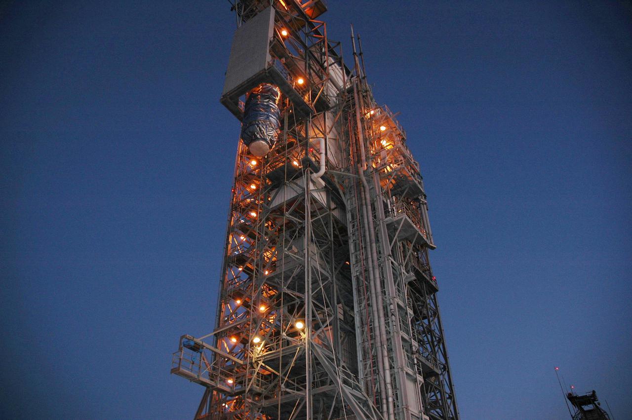 KENNEDY SPACE CENTER, FLA. - The Deep Impact spacecraft is lifted into the top of the mobile service tower on Launch Pad 17-B at Cape Canaveral Air Force Station, Fla.  the spacecraft will be attached to the second stage of the Boeing Delta II rocket.  Next the fairing will be installed around the spacecraft.  The fairing is a molded structure that fits flush with the outside surface of the Delta II upper stage booster and forms an aerodynamically smooth joint, protecting the spacecraft during launch and ascent.  Scheduled for liftoff Jan. 12,  Deep Impact will probe beneath the surface of Comet Tempel 1 on July 4, 2005, when the comet is 83 million miles from Earth.  After releasing a 3- by 3-foot projectile to crash onto the surface, Deep Impact’s flyby spacecraft will reveal the secrets of its interior by collecting pictures and data of how the crater forms, measuring the crater’s depth and diameter as well as the composition of the interior of the crater and any material thrown out, and determining the changes in natural outgassing produced by the impact.  It will send the data back to Earth through the antennas of the Deep Space Network.  Deep Impact is a NASA Discovery mission.