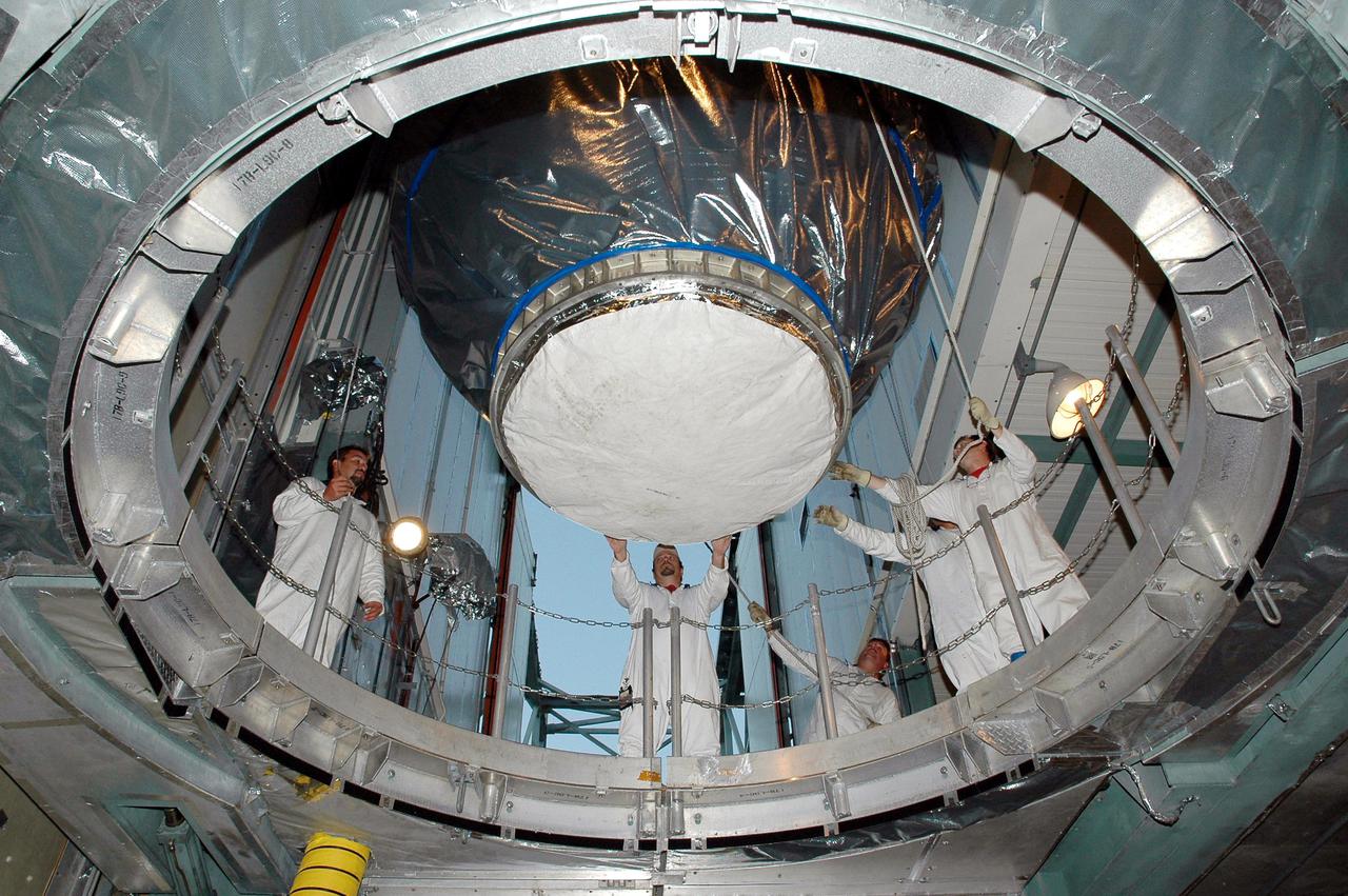 KENNEDY SPACE CENTER, FLA. - In the mobile service tower on Launch Pad 17-B at Cape Canaveral Air Force Station, Fla., workers begin lowering the Deep Impact spacecraft toward the second stage of the Boeing Delta II launch vehicle below for mating. Next the fairing will be installed around the spacecraft.  The fairing is a molded structure that fits flush with the outside surface of the Delta II upper stage booster and forms an aerodynamically smooth joint, protecting the spacecraft during launch and ascent.  Scheduled for liftoff Jan. 12,  Deep Impact will probe beneath the surface of Comet Tempel 1 on July 4, 2005, when the comet is 83 million miles from Earth.  After releasing a 3- by 3-foot projectile to crash onto the surface, Deep Impact’s flyby spacecraft will reveal the secrets of its interior by collecting pictures and data of how the crater forms, measuring the crater’s depth and diameter as well as the composition of the interior of the crater and any material thrown out, and determining the changes in natural outgassing produced by the impact.  It will send the data back to Earth through the antennas of the Deep Space Network.  Deep Impact is a NASA Discovery mission.