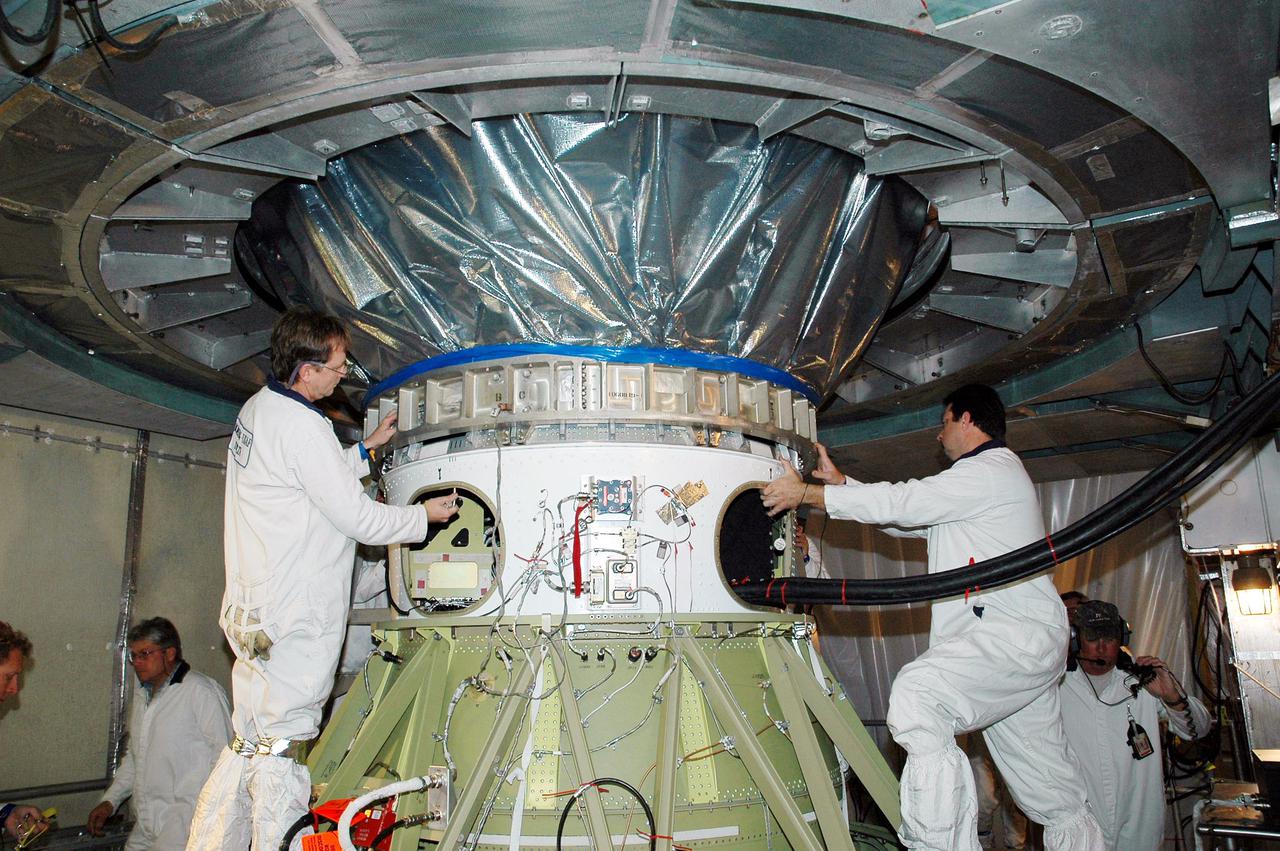 KENNEDY SPACE CENTER, FLA. - In the mobile service tower on Launch Pad 17-B at Cape Canaveral Air Force Station, Fla., workers attach the third stage motor, connected to the Deep Impact spacecraft, to the spin table on the second stage of the Boeing Delta II launch vehicle below. Next the fairing will be installed around the spacecraft.  The fairing is a molded structure that fits flush with the outside surface of the Delta II upper stage booster and forms an aerodynamically smooth joint, protecting the spacecraft during launch and ascent.  Scheduled for liftoff Jan. 12,  Deep Impact will probe beneath the surface of Comet Tempel 1 on July 4, 2005, when the comet is 83 million miles from Earth.  After releasing a 3- by 3-foot projectile to crash onto the surface, Deep Impact’s flyby spacecraft will reveal the secrets of its interior by collecting pictures and data of how the crater forms, measuring the crater’s depth and diameter as well as the composition of the interior of the crater and any material thrown out, and determining the changes in natural outgassing produced by the impact.  It will send the data back to Earth through the antennas of the Deep Space Network.  Deep Impact is a NASA Discovery mission.