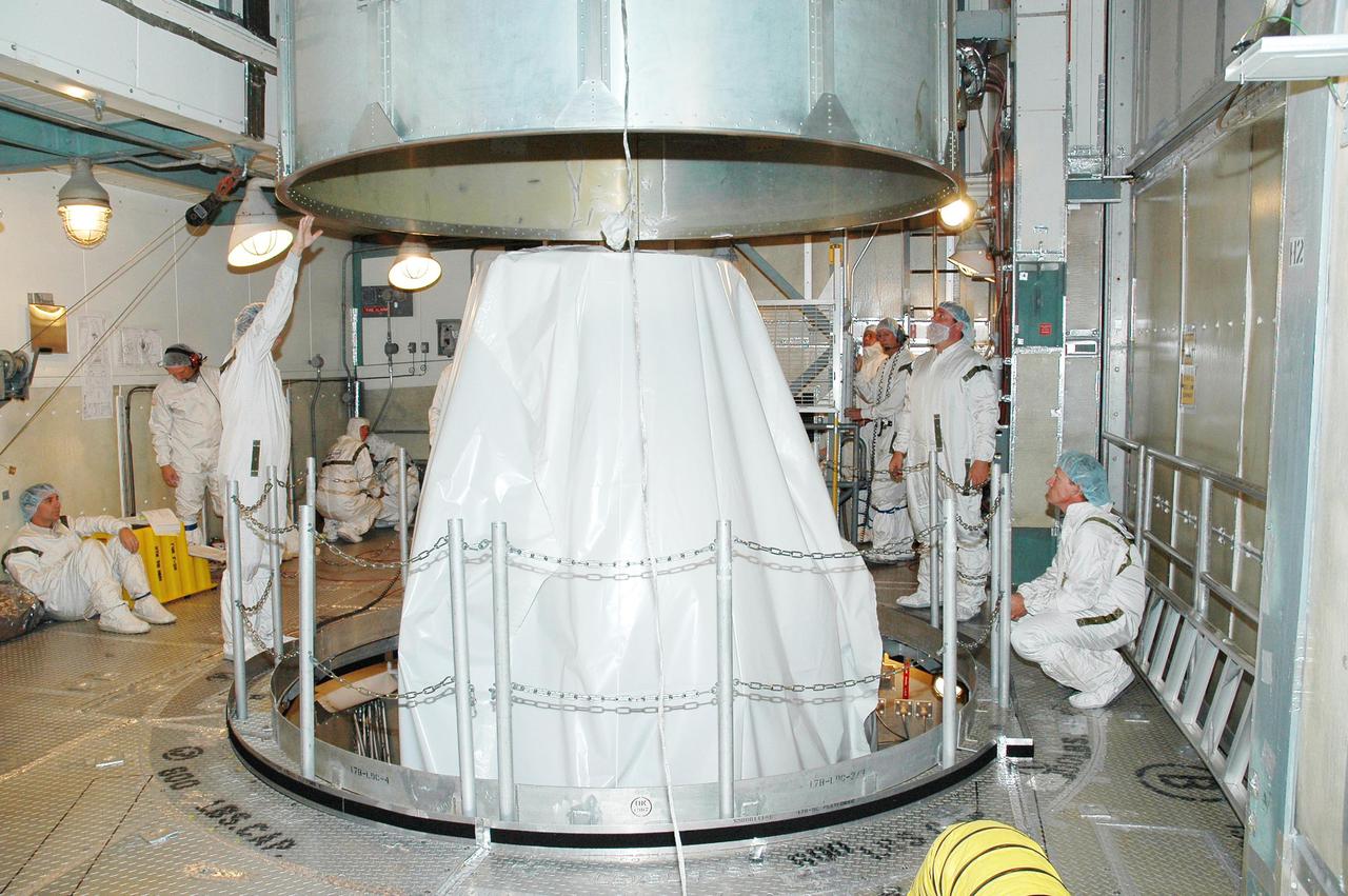 KENNEDY SPACE CENTER, FLA. - In the mobile service tower on Launch Pad 17-B at Cape Canaveral Air Force Station, Fla., workers stand by as the canister is lifted away from the Deep Impact spacecraft. Next the fairing will be installed around the spacecraft.  The fairing is a molded structure that fits flush with the outside surface of the Delta II upper stage booster and forms an aerodynamically smooth joint, protecting the spacecraft during launch and ascent.  Scheduled for liftoff Jan. 12,  Deep Impact will probe beneath the surface of Comet Tempel 1 on July 4, 2005, when the comet is 83 million miles from Earth.  After releasing a 3- by 3-foot projectile to crash onto the surface, Deep Impact’s flyby spacecraft will reveal the secrets of its interior by collecting pictures and data of how the crater forms, measuring the crater’s depth and diameter as well as the composition of the interior of the crater and any material thrown out, and determining the changes in natural outgassing produced by the impact.  It will send the data back to Earth through the antennas of the Deep Space Network.  Deep Impact is a NASA Discovery mission.