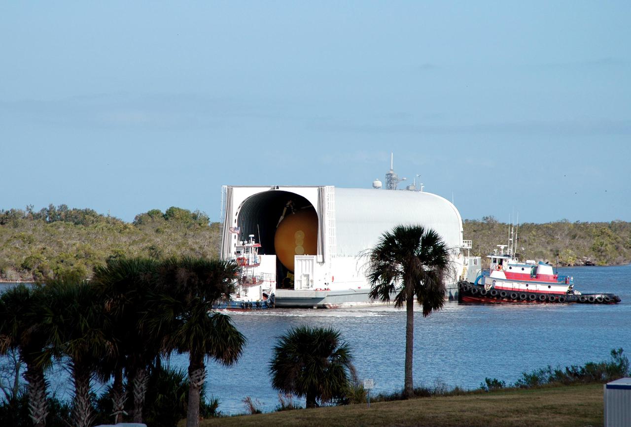 KENNEDY SPACE CENTER, FLA. - A tugboat maneuvers the barge carrying the newly redesigned External Tank (ET), designated for use on Return to Flight mission STS-114, toward the dock at the Launch Complex 39 Area Turn Basin. The ET can be seen inside the barge. The External Tank arrived safely early this morning at Port Canaveral, Fla., after an approximately 900-mile journey at sea. It departed from the Michoud Assembly Facility in New Orleans Dec. 31 and was transported on the Pegasus, NASA’s specially designed barge, pulled by Solid Rocket Booster retrieval ship Liberty Star. At the port, the barge was then hooked up to the tugs for the last part of the journey to the Turn Basin. Next, the External Tank will be off-loaded from the barge and transported to the Vehicle Assembly Building for its final checkout and mating to the twin Solid Rocket Boosters and orbiter Discovery. NASA and Lockheed Martin Corp. spent nearly two years modifying the 15-story, bronze-colored tank to make it safer for liftoff. Among dozens of changes is a redesigned forward bipod fitting -- a design that meets the recommendation of the Columbia Accident Investigation Board to reduce the risk to the Space Shuttle from falling debris during ascent. STS-114 is targeted for a launch opportunity beginning in May. The seven-member Discovery crew will fly to the International Space Station primarily to test and evaluate new procedures for flight safety, including Space Shuttle inspection and repair techniques.