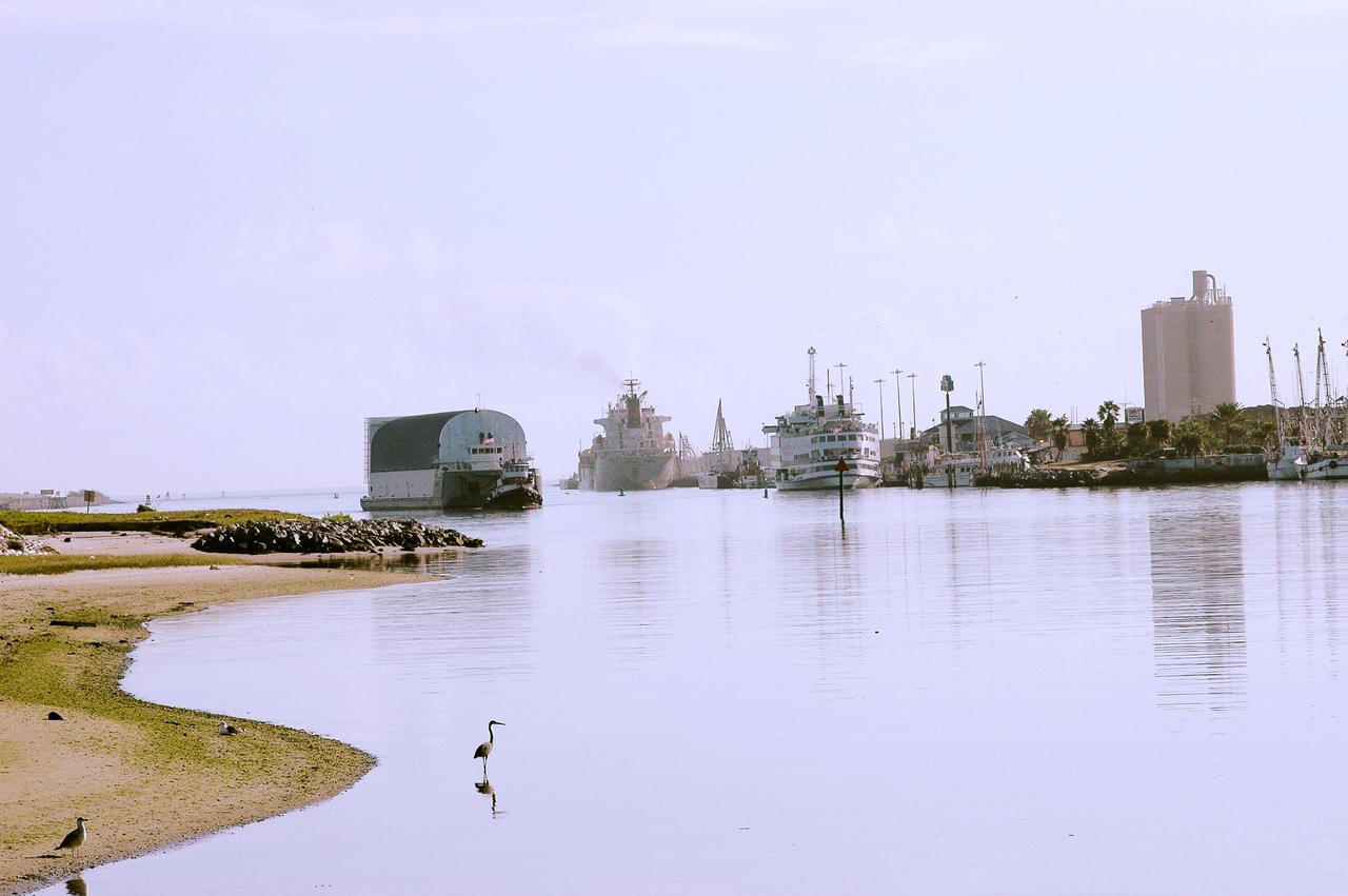 KENNEDY SPACE CENTER, FLA. - The barge carrying the newly redesigned External Tank, designated for use on Return to Flight mission STS-114, passes cruise ships as it enters Port Canaveral, Fla. The barge arrived after an approximately 900-mile journey at sea from the Michoud Assembly Facility in New Orleans. It left the facility Dec. 31 on the Pegasus, NASA’s specially designed barge, towed by Solid Rocket Booster retrieval ship Liberty Star. At Port Canaveral, the barge was then hooked up to the tugs for the last part of the journey to the Launch Complex 39 Area Turn Basin at Kennedy. Next, the External Tank will be off-loaded from the barge and transported to the Vehicle Assembly Building for its final checkout and mating to the twin Solid Rocket Boosters and orbiter Discovery. NASA and Lockheed Martin Corp. spent nearly two years modifying the 15-story, bronze-colored tank to make it safer for liftoff. Among dozens of changes is a redesigned forward bipod fitting -- a design that meets the recommendation of the Columbia Accident Investigation Board to reduce the risk to the Space Shuttle from falling debris during ascent. STS-114 is targeted for a launch opportunity beginning in May. The seven-member Discovery crew will fly to the International Space Station primarily to test and evaluate new procedures for flight safety, including Space Shuttle inspection and repair techniques.