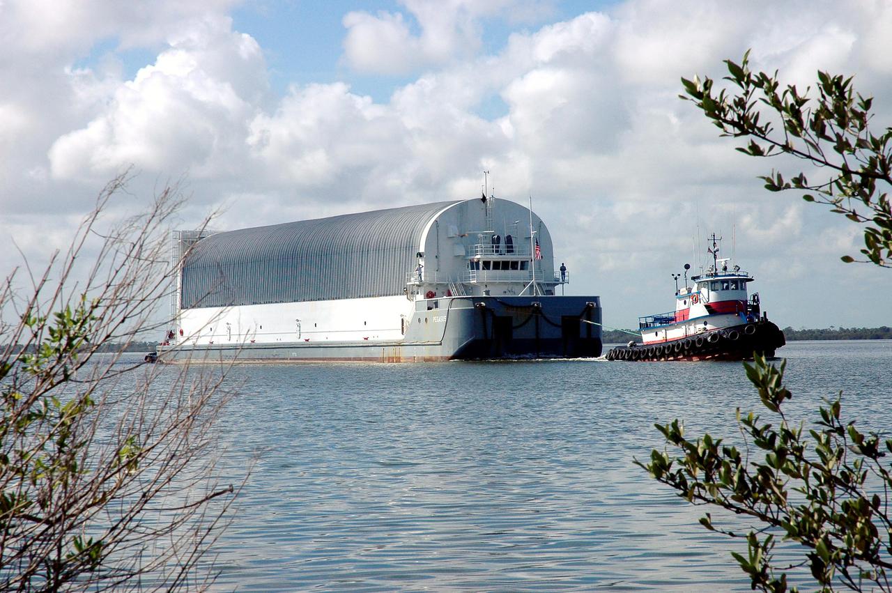 KENNEDY SPACE CENTER, FLA. - A tugboat tows the barge carrying the newly redesigned External Tank, designated for use on Return to Flight mission STS-114, to the dock at the Launch Complex 39 Area Turn Basin at Kennedy. The barge arrived after an approximately 900-mile journey at sea from the Michoud Assembly Facility in New Orleans. It left the facility Dec. 31 on the Pegasus, NASA’s specially designed barge, towed by Solid Rocket Booster retrieval ship Liberty Star. At Port Canaveral, the barge was then hooked up to the tugs for the last part of the journey to the Launch Complex 39 Area Turn Basin at Kennedy. Next, the External Tank will be off-loaded from the barge and transported to the Vehicle Assembly Building for its final checkout and mating to the twin Solid Rocket Boosters and orbiter Discovery. NASA and Lockheed Martin Corp. spent nearly two years modifying the 15-story, bronze-colored tank to make it safer for liftoff. Among dozens of changes is a redesigned forward bipod fitting -- a design that meets the recommendation of the Columbia Accident Investigation Board to reduce the risk to the Space Shuttle from falling debris during ascent. STS-114 is targeted for a launch opportunity beginning in May. The seven-member Discovery crew will fly to the International Space Station primarily to test and evaluate new procedures for flight safety, including Space Shuttle inspection and repair techniques.