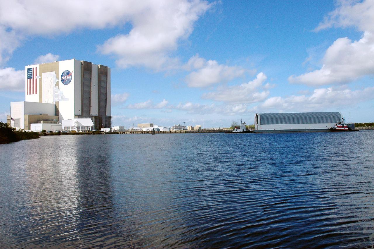 KENNEDY SPACE CENTER, FLA. - The barge carrying the newly redesigned External Tank, designated for use on Return to Flight mission STS-114, is towed toward the Launch Complex 39 Area Turn Basin at Kennedy. At left is the Vehicle Assembly Building. The barge arrived after an approximately 900-mile journey at sea from the Michoud Assembly Facility in New Orleans. It left the facility Dec. 31 on the Pegasus, NASA’s specially designed barge, towed by Solid Rocket Booster retrieval ship Liberty Star. At Port Canaveral, the barge was then hooked up to the tugs for the last part of the journey. Next, the External Tank will be off-loaded from the barge and transported to the Vehicle Assembly Building for its final checkout and mating to the twin Solid Rocket Boosters and orbiter Discovery. NASA and Lockheed Martin Corp. spent nearly two years modifying the 15-story, bronze-colored tank to make it safer for liftoff. Among dozens of changes is a redesigned forward bipod fitting -- a design that meets the recommendation of the Columbia Accident Investigation Board to reduce the risk to the Space Shuttle from falling debris during ascent. STS-114 is targeted for a launch opportunity beginning in May. The seven-member Discovery crew will fly to the International Space Station primarily to test and evaluate new procedures for flight safety, including Space Shuttle inspection and repair techniques.