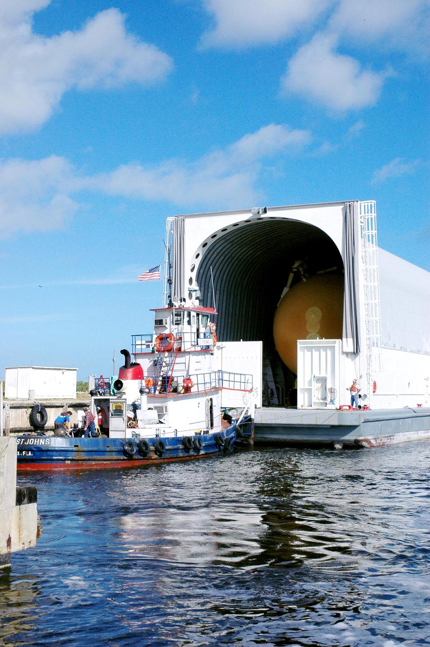 KENNEDY SPACE CENTER, FLA. - Tugboats maneuver the barge carrying the newly redesigned External Tank (ET), designated for use on Return to Flight mission STS-114, closer to the dock at the Launch Complex 39 Area Turn Basin. The ET can be seen inside the barge. The External Tank arrived safely early this morning at Port Canaveral, Fla., after an approximately 900-mile journey at sea. It departed from the Michoud Assembly Facility in New Orleans Dec. 31 and was transported on the Pegasus, NASA’s specially designed barge, pulled by Solid Rocket Booster retrieval ship Liberty Star. At the port, the barge was then hooked up to the tugs for the last part of the journey to the Turn Basin. Next, the External Tank will be off-loaded from the barge and transported to the Vehicle Assembly Building for its final checkout and mating to the twin Solid Rocket Boosters and orbiter Discovery. NASA and Lockheed Martin Corp. spent nearly two years modifying the 15-story, bronze-colored tank to make it safer for liftoff. Among dozens of changes is a redesigned forward bipod fitting -- a design that meets the recommendation of the Columbia Accident Investigation Board to reduce the risk to the Space Shuttle from falling debris during ascent. STS-114 is targeted for a launch opportunity beginning in May. The seven-member Discovery crew will fly to the International Space Station primarily to test and evaluate new procedures for flight safety, including Space Shuttle inspection and repair techniques.