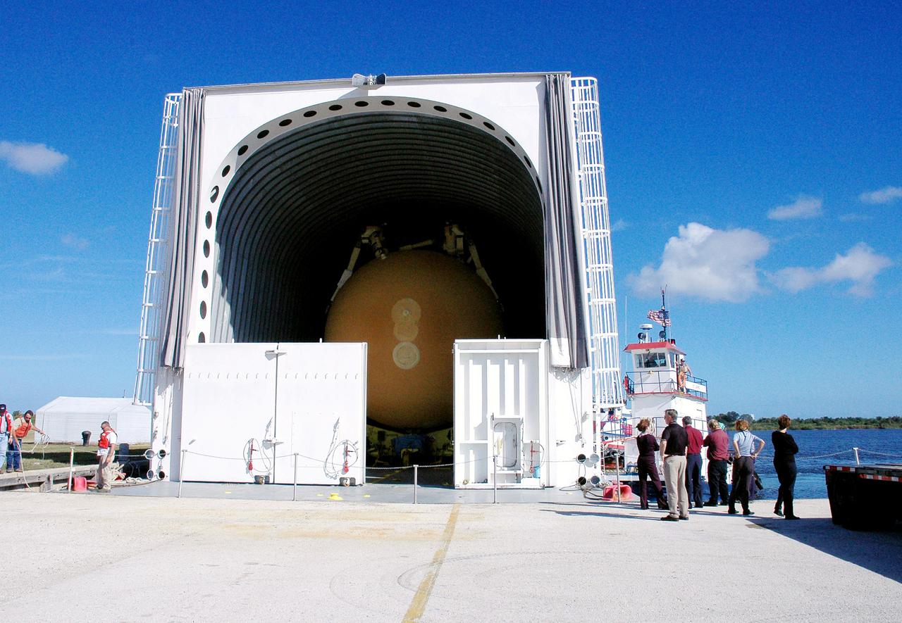 KENNEDY SPACE CENTER, FLA. - The barge carrying the newly redesigned External Tank (ET), designated for use on Return to Flight mission STS-114, is finally docked at the Launch Complex 39 Area Turn Basin. The ET can be seen inside the barge. The External Tank arrived safely early this morning at Port Canaveral, Fla., after an approximately 900-mile journey at sea. It departed from the Michoud Assembly Facility in New Orleans Dec. 31 and was transported on the Pegasus, NASA’s specially designed barge, pulled by Solid Rocket Booster retrieval ship Liberty Star. At the port, the barge was then hooked up to the tugs for the last part of the journey. Next, the External Tank will be off-loaded from the barge and transported to the Vehicle Assembly Building for its final checkout and mating to the twin Solid Rocket Boosters and orbiter Discovery. NASA and Lockheed Martin Corp. spent nearly two years modifying the 15-story, bronze-colored tank to make it safer for liftoff. Among dozens of changes is a redesigned forward bipod fitting -- a design that meets the recommendation of the Columbia Accident Investigation Board to reduce the risk to the Space Shuttle from falling debris during ascent. STS-114 is targeted for a launch opportunity beginning in May. The seven-member Discovery crew will fly to the International Space Station primarily to test and evaluate new procedures for flight safety, including Space Shuttle inspection and repair techniques.