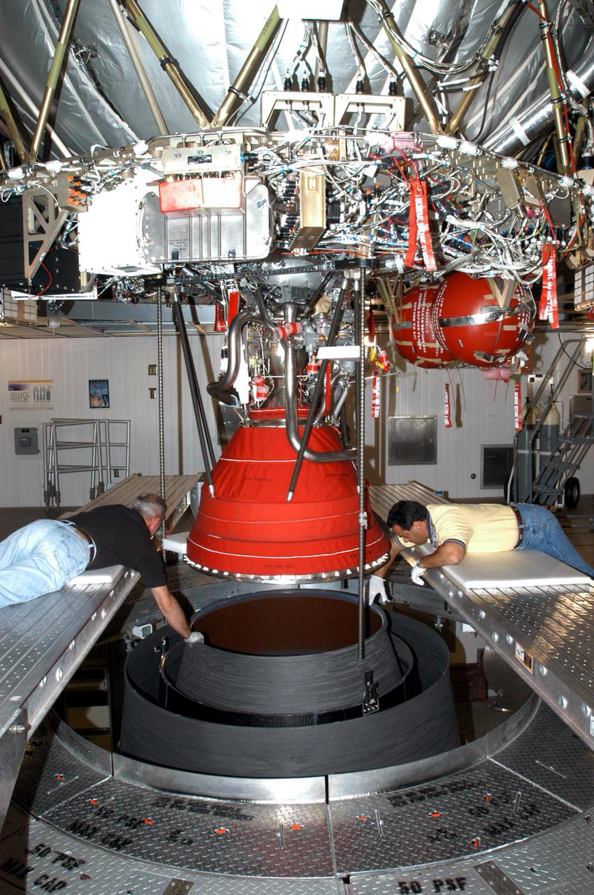 KENNEDY SPACE CENTER, FLA. - At the Delta Operations Center, Jack Reynolds and Leslie Guzman (left and right), with Pratt and Whitney, closely guide the nozzle for the RL-10 engine on the second stage of the Boeing Delta IV rocket.  The Delta IV is the launch vehicle for the Geostationary Operational Environmental Satellite (GOES-N), scheduled to launch in April 2005 from Cape Canaveral Air Force Station.  GOES-N is a weather satellite for NASA and NOAA (National Oceanic and Atmospheric Administration).  The first in a series of three advanced weather satellites including GOES-O and GOES-P, the GOES-N will provide continuous monitoring necessary for intensive data analysis. It will provide a constant vigil for the atmospheric “triggers” of severe weather conditions such as tornadoes, flash floods, hail storms and hurricanes. When these conditions develop, GOES-N will be able to monitor storm development and track their movements.