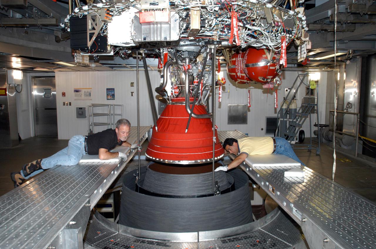 KENNEDY SPACE CENTER, FLA. - At the Delta Operations Center, Jack Reynolds and Leslie Guzman (left and right), with Pratt and Whitney, closely guide the nozzle for the RL-10 engine on the second stage of the Boeing Delta IV rocket.  The Delta IV is the launch vehicle for the Geostationary Operational Environmental Satellite (GOES-N), scheduled to launch in April 2005 from Cape Canaveral Air Force Station.  GOES-N is a weather satellite for NASA and NOAA (National Oceanic and Atmospheric Administration).  The first in a series of three advanced weather satellites including GOES-O and GOES-P, the GOES-N will provide continuous monitoring necessary for intensive data analysis. It will provide a constant vigil for the atmospheric “triggers” of severe weather conditions such as tornadoes, flash floods, hail storms and hurricanes. When these conditions develop, GOES-N will be able to monitor storm development and track their movements.