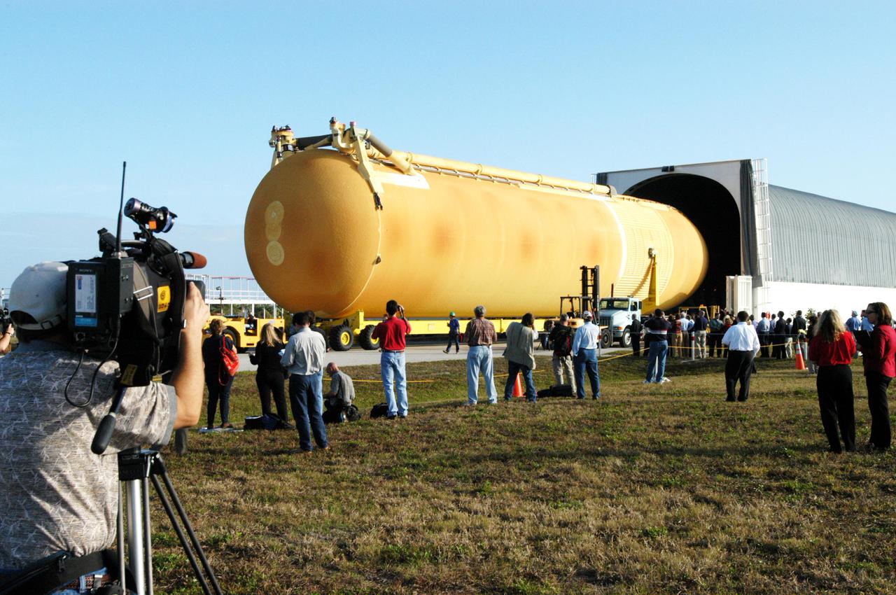 KENNEDY SPACE CENTER, FLA. - Media view the newly redesigned External Tank as it is off-loaded from the barge that carried it from the Michoud Assembly Facility in New Orleans.  The tank is being transported to the Vehicle Assembly Building.  The tank arrived Jan. 5 after a 900-mile sea voyage aboard NASA’s specially designed barge, Pegasus, from the Michoud Assembly Facility in New Orleans.  In the transfer aisle of the VAB, the tank will be raised from a horizontal to a vertical position, then lifted high up into a storage cell, or “checkout cell,” where it will undergo inspections of the mechanical, electrical and thermal protection systems.  New processing activities resulting from re-design of the tank include inspection of the bipod heater and External Tank separation camera, which includes charging the camera batteries.  The tank will be then prepared for mating to the Solid Rocket Boosters.  When preparations are complete, the tank will be lifted from the checkout cell, moved across the transfer aisle and into High Bay 1, where it will be lowered and attached to the boosters, which are sitting on the Mobile Launch Platform.  The tank is designated for the Return to Flight mission, STS-114,  targeted for a launch opportunity beginning in May. The seven-member Discovery crew will fly to the International Space Station primarily to test and evaluate new procedures for flight safety, including Space Shuttle inspection and repair techniques.