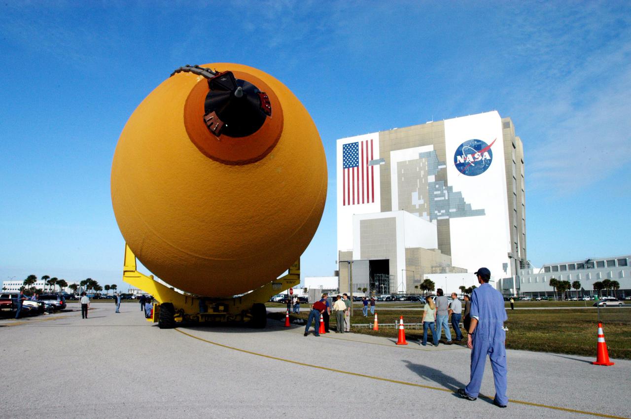 KENNEDY SPACE CENTER, FLA. - The newly redesigned External Tank slowly moves toward the Vehicle Assembly Building, seen at right.  The tank arrived Jan. 5 after a 900-mile sea voyage aboard NASA’s specially designed barge, Pegasus, from the Michoud Assembly Facility in New Orleans.  In the transfer aisle of the VAB, the tank will be raised from a horizontal to a vertical position, then lifted high up into a storage cell, or “checkout cell,” where it will undergo inspections of the mechanical, electrical and thermal protection systems.  New processing activities resulting from re-design of the tank include inspection of the bipod heater and External Tank separation camera, which includes charging the camera batteries.  The tank will be then prepared for mating to the Solid Rocket Boosters.  When preparations are complete, the tank will be lifted from the checkout cell, moved across the transfer aisle and into High Bay 1, where it will be lowered and attached to the boosters, which are sitting on the Mobile Launch Platform.  The tank is designated for the Return to Flight mission, STS-114,  targeted for a launch opportunity beginning in May. The seven-member Discovery crew will fly to the International Space Station primarily to test and evaluate new procedures for flight safety, including Space Shuttle inspection and repair techniques.