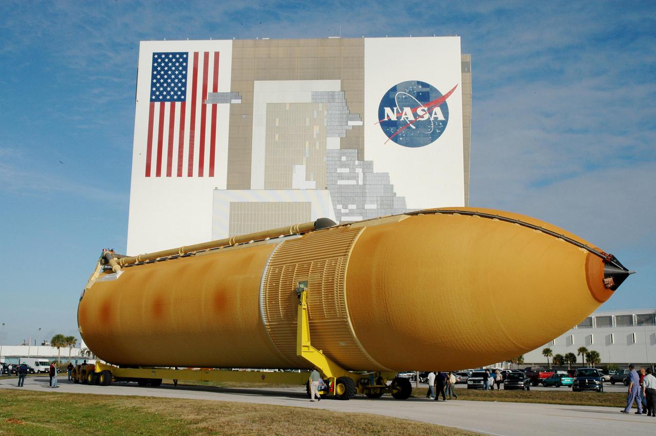 KENNEDY SPACE CENTER, FLA. - The newly redesigned External Tank moves closer to its destination, the Vehicle Assembly Building, seen behind it. The tank arrived Jan. 5 after a 900-mile sea voyage aboard NASA’s specially designed barge, Pegasus, from the Michoud Assembly Facility in New Orleans.  In the transfer aisle of the VAB, the tank will be raised from a horizontal to a vertical position, then lifted high up into a storage cell, or “checkout cell,” where it will undergo inspections of the mechanical, electrical and thermal protection systems.  New processing activities resulting from re-design of the tank include inspection of the bipod heater and External Tank separation camera, which includes charging the camera batteries.  The tank will be then prepared for mating to the Solid Rocket Boosters.  When preparations are complete, the tank will be lifted from the checkout cell, moved across the transfer aisle and into High Bay 1, where it will be lowered and attached to the boosters, which are sitting on the Mobile Launch Platform.  The tank is designated for the Return to Flight mission, STS-114,  targeted for a launch opportunity beginning in May. The seven-member Discovery crew will fly to the International Space Station primarily to test and evaluate new procedures for flight safety, including Space Shuttle inspection and repair techniques.