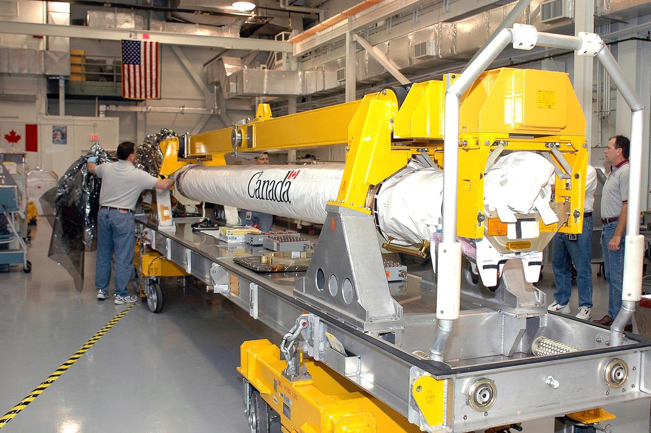 KENNEDY SPACE CENTER, FLA. - Todd Dugan, United Space Alliance technician, removes the cover from the Orbiter Boom Sensor System in the Remote Manipulator System lab. The OBSS is undergoing final checkout and testing in the lab prior to being transferred to the Orbiter Processing Facility for installation on Space Shuttle Discovery. The 50-foot-long OBSS will be attached to the Remote Manipulator System, or Shuttle arm, and is one of the new safety measures for Return to Flight, equipping the orbiter with cameras and laser systems to inspect the Shuttle's Thermal Protection System while in space. Discovery is slated to fly mission STS-114 once Space Shuttle launches resume. The launch planning window is May 12 to June 3, 2005.