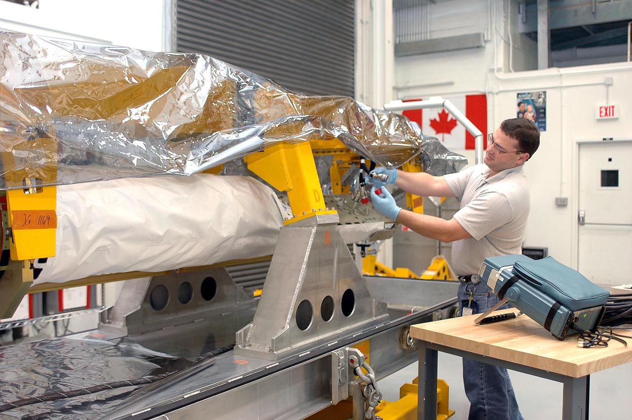 KENNEDY SPACE CENTER, FLA. - In the Remote Manipulator System lab, United Space Alliance technician Todd Dugan works on the Orbiter Boom Sensor System. The OBSS is undergoing final checkout and testing in the lab prior to being transferred to the Orbiter Processing Facility for installation on Space Shuttle Discovery. The 50-foot-long OBSS will be attached to the Remote Manipulator System, or Shuttle arm, and is one of the new safety measures for Return to Flight, equipping the orbiter with cameras and laser systems to inspect the Shuttle's Thermal Protection System while in space. Discovery is slated to fly mission STS-114 once Space Shuttle launches resume. The launch planning window is May 12 to June 3, 2005.