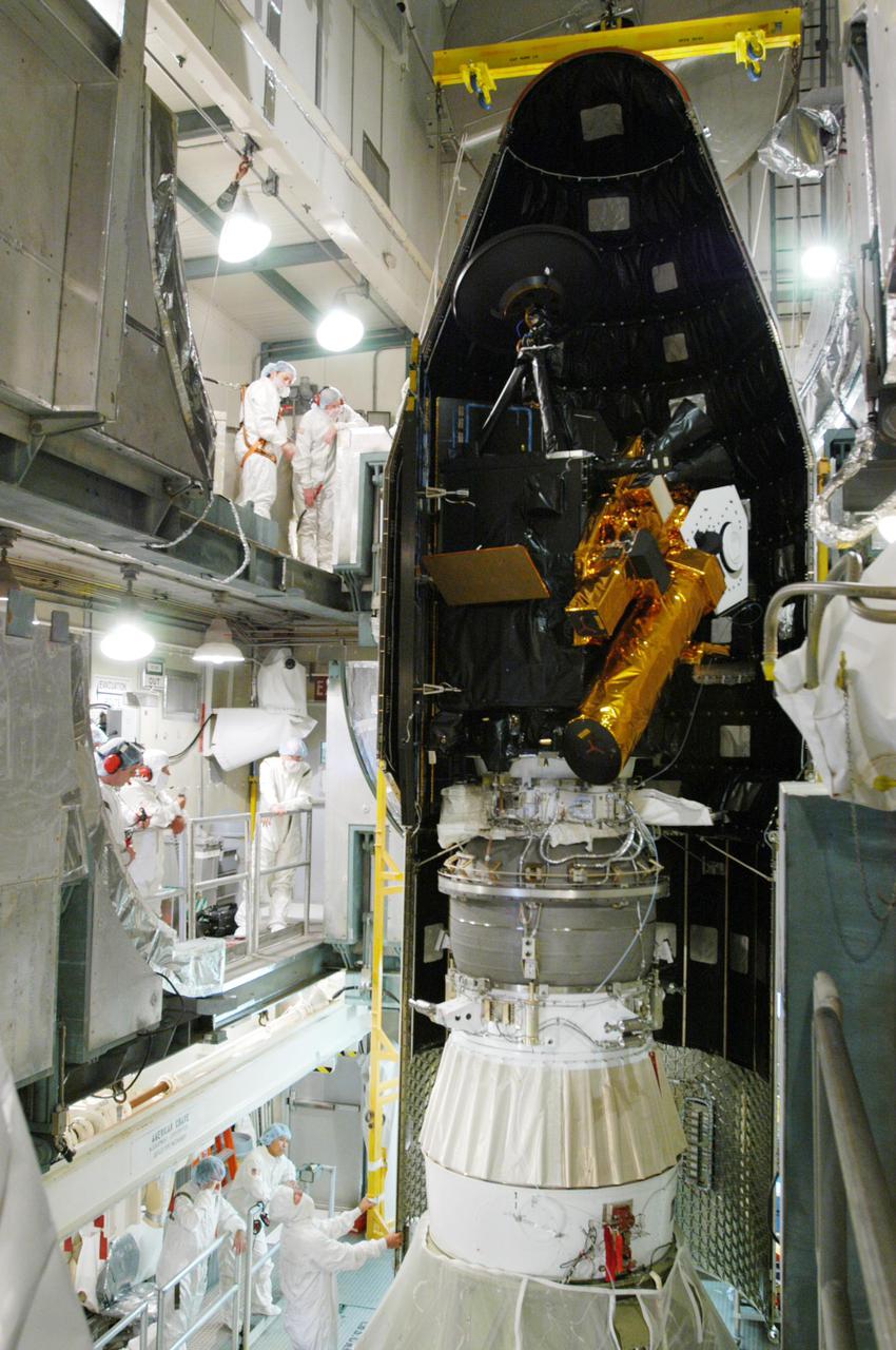 KENNEDY SPACE CENTER, FLA. -Inside the mobile service tower on Launch Pad 17-B, Cape Canaveral Air force Station, Fla., the first half of the fairing is moved into place around the Deep Impact spacecraft. The fairing is a molded structure that fits flush with the outside surface of the Delta II upper stage booster and forms an aerodynamically smooth nosecone, protecting the spacecraft during launch and ascent. Scheduled for liftoff Jan. 12, Deep Impact will probe beneath the surface of Comet Tempel 1 on July 4, 2005, when the comet is 83 million miles from Earth. After releasing a 3- by 3-foot projectile to crash onto the surface, Deep Impact’s flyby spacecraft will reveal the secrets of its interior by collecting pictures and data of how the crater forms, measuring the crater’s depth and diameter as well as the composition of the interior of the crater and any material thrown out, and determining the changes in natural outgassing produced by the impact. It will send the data back to Earth through the antennas of the Deep Space Network. Deep Impact is a NASA Discovery mission.