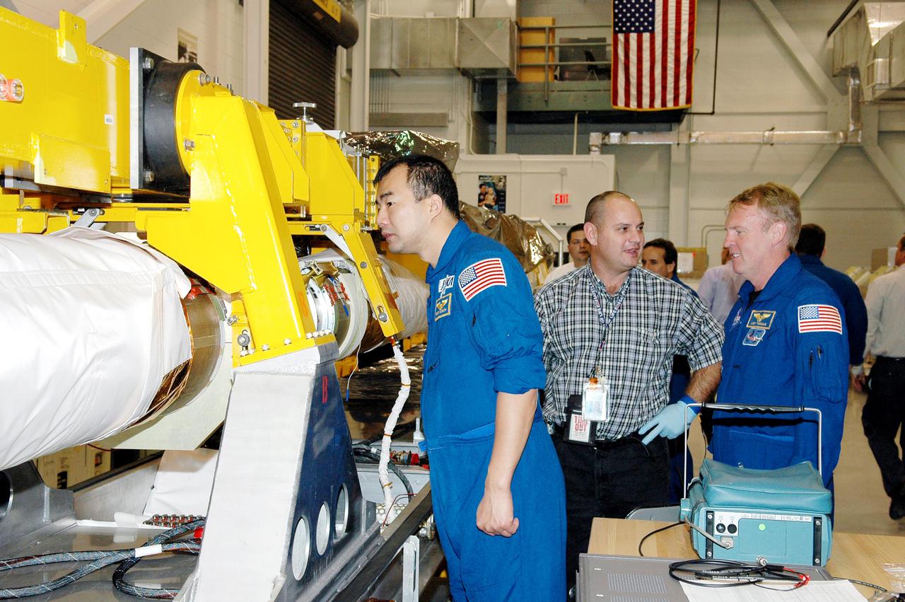 KENNEDY SPACE CENTER, FLA. - In the Remote Manipulator Lab inside the Vehicle Assembly Building, STS-114 Mission Specialists Soichi Noguchi (left) and Andrew Thomas (far right) get a close look at about the 50-foot-long Orbiter Boom Sensor System (OBSS) that will fly on Shuttle Discovery on Return to Flight mission STS-114.   Between them is Rafael Rodriguez, an advanced systems technician with United Space Alliance. The OBSS attaches to the end of the Shuttle’s robotic arm.  The system is one of the new safety measures for Return to Flight, equipping the orbiter with cameras and laser systems to inspect the Shuttle’s Thermal Protection System while in space. The mission launch window is May 12 to June 3, 2005.