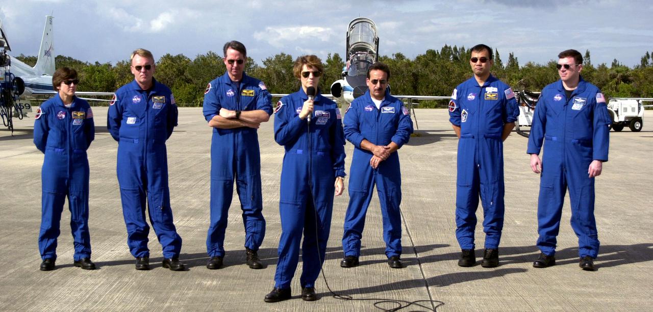 KENNEDY SPACE CENTER, FLA. - At the Shuttle Landing Facility, STS-114 Mission Commander Eileen Collins talks to reporters before the crew departs Kennedy Space Center.  Behind Collins are, left to right, Mission Specialists Wendy Lawrence, Andrew Thomas, Stephen Robinson, Charles Camardo and Sochi Noguchi, and Pilot James Kelly.  Noguchi is with the Japanese Space Agency.  The crew was at KSC to observe the newly redesigned External Tank and new 50-foot-long Orbiter Boom Sensor System (OBSS).  Among redesign changes on the ET is the forward bipod fitting to reduce the risk to the Shuttle from falling debris during ascent.  A camera has also been added to capture separation of the ET from the Shuttle after launch.  The OBSS attaches to the end of the Shuttle’s robotic arm and  equips the orbiter with cameras and laser systems to inspect the Shuttle’s Thermal Protection System while in space.  The launch window for Return to Flight mission STS-114 is May 12 to June 3, 2005.  (Photo: Michael R. Brown)