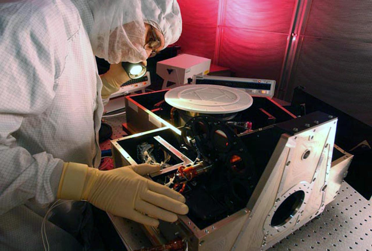 JET PROPULSION LABORATORY, CALIF. - At Ball Aerospace in Boulder, Colo., the infrared (IR) spectrometer for the Deep Impact flyby spacecraft is inspected in the instrument assembly area in the Fisher Assembly building clean room.  Deep Impact will probe beneath the surface of Comet Tempel 1 on July 4, 2005, when the comet is 83 million miles from Earth, and reveal the secrets of its interior. After releasing a 3- by 3-foot projectile to crash onto the surface, Deep Impact’s flyby spacecraft will collect pictures and data of how the crater forms, measuring the crater’s depth and diameter, as well as the composition of the interior of the crater and any material thrown out, and determining the changes in natural outgassing produced by the impact.  The spectrometer is part of the High Resolution Instrument in the spacecraft. This imager will be aimed at the ejected matter as the crater forms, and an infrared 'fingerprint' of the material from inside of the comet's nucleus will be taken.  It will send the data back to Earth through the antennas of the Deep Space Network.   Deep Impact is a NASA Discovery mission. Launch of Deep Impact is scheduled for Jan. 12 from Launch Pad 17-B, Cape Canaveral Air Force Station, Fla.