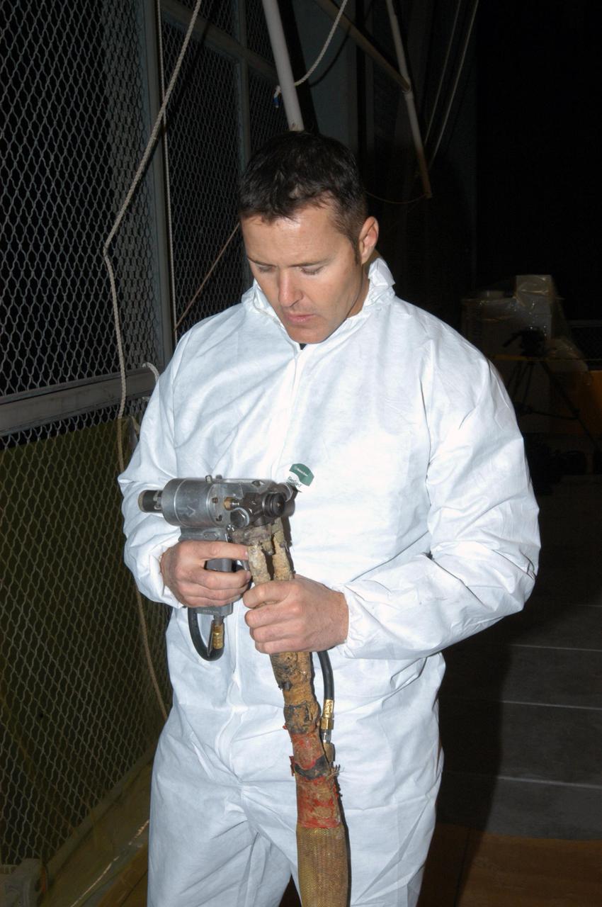 KENNEDY SPACE CENTER, FLA.  -  In the Vehicle Assembly Building, United Space Alliance technician Ed Carillion attaches the foam spray nozzle to the spray gun to be used for the aft hard-point closeout spray on the External Tank (ET).  The spray is being applied on an area of the tank where the ET is mated to the transporter.  Foam is not applied to that area at the Michoud Assembly Facility in Louisiana to avoid damage to the foam during travel.  The ET, which arrived at KSC Jan. 5, is in the checkout cell for final processing.  The tank is scheduled to fly on Space Shuttle Discovery on Return to Flight mission STS-114.  The launch window is May 12 to June 3.