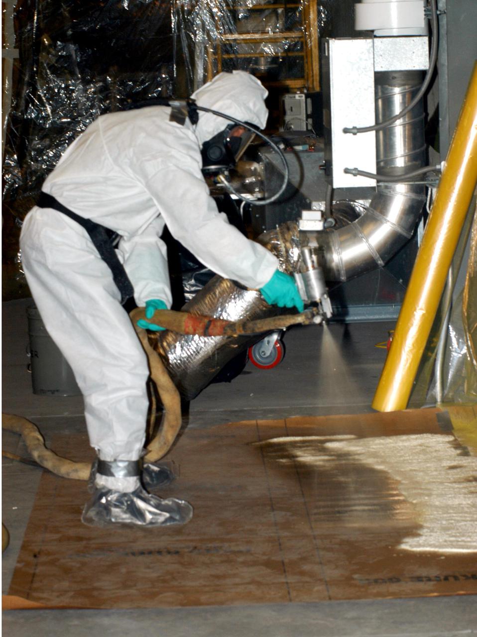 KENNEDY SPACE CENTER, FLA.  - In the Vehicle Assembly Building, United Space Alliance technician Rob Williams tests the spray gun before starting aft hard-point closeout spray on the External Tank (ET).The spray is being applied on an area of the tank where the ET is mated to the transporter.  Foam is not applied to that area at the Michoud Assembly Facility in Louisiana to avoid damage to the foam during travel.  The ET, which arrived at KSC Jan. 5, is in the checkout cell for final processing.  The tank is scheduled to fly on Space Shuttle Discovery on Return to Flight mission STS-114.  The launch window is May 12 to June 3.