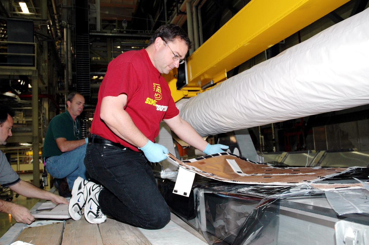 KENNEDY SPACE CENTER, FLA. - In the back transfer aisle of the Orbiter Processing Facility bay 3, Todd Dugan, a technician with United Space Alliance, prepares the Thermal Protection System (TPS) blanket to be installed around the Orbiter Boom Sensor System (OBSS). The installation concludes TPS closeout prior to installation of the boom in the orbiter Discovery. The OBSS is one of the new safety measures for Return to Flight, equipping the Shuttle with cameras and laser systems to inspect the Shuttle’s Thermal Protection System while in space. Discovery is designated as the Return to Flight vehicle for mission STS-114, with a launch window of May 12 to June 3, 2005.