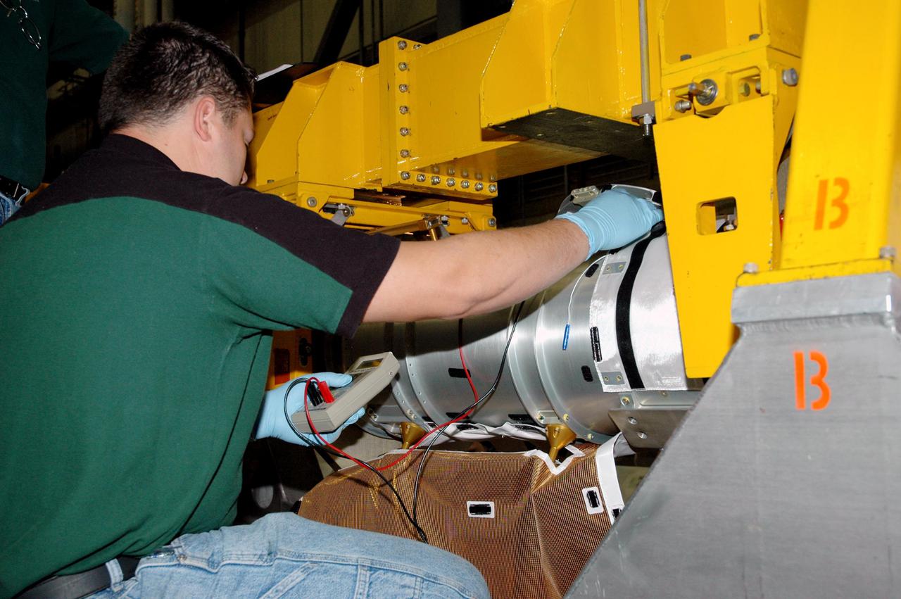 KENNEDY SPACE CENTER, FLA. - In the back transfer aisle of the Orbiter Processing Facility bay 3, a worker checks the resistance measurement of one of the Thermal Protection System (TPS) blanket ground wires to ensure a proper ground between the blanket to be installed and the Orbiter Boom Sensor System (OBSS). The installation will conclude TPS closeout prior to installation of the boom in the orbiter Discovery. The OBSS is one of the new safety measures for Return to Flight, equipping the Shuttle with cameras and laser systems to inspect the Shuttle’s Thermal Protection System while in space. Discovery is designated as the Return to Flight vehicle for mission STS-114, with a launch window of May 12 to June 3, 2005.