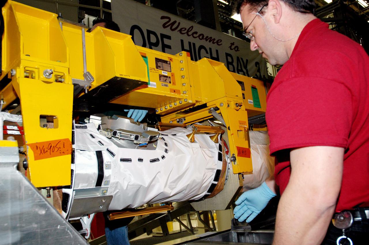 KENNEDY SPACE CENTER, FLA. - In the back transfer aisle of the Orbiter Processing Facility bay 3, Todd Dugan, a technician with United Space Alliance, checks out the Thermal Protection System (TPS) blanket wrapped around the Orbiter Boom Sensor System (OBSS). The installation of the insulation concludes TPS closeout prior to installation of the boom in the orbiter Discovery. The OBSS is one of the new safety measures for Return to Flight, equipping the Shuttle with cameras and laser systems to inspect the Shuttle’s Thermal Protection System while in space. Discovery is designated as the Return to Flight vehicle for mission STS-114, with a launch window of May 12 to June 3, 2005.