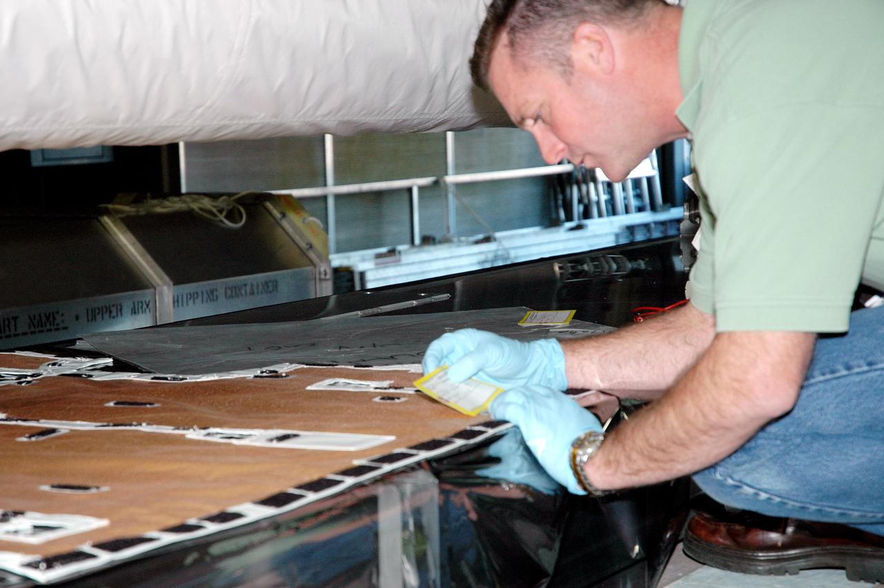 KENNEDY SPACE CENTER, FLA.  - In the back transfer aisle of the Orbiter Processing Facility bay 3, a worker checks paperwork for the Thermal Protection System (TPS) blanket to be wrapped around the Orbiter Boom Sensor System (OBSS).  The installation of the insulation concludes TPS closeout prior to installation of the boom in the orbiter Discovery.  The OBSS is one of the new safety measures for Return to Flight, equipping the Shuttle with cameras and laser systems to inspect the Shuttle’s Thermal Protection System while in space.  Discovery is designated as the Return to Flight vehicle for mission STS-114, with a launch window of May 12 to June 3, 2005.