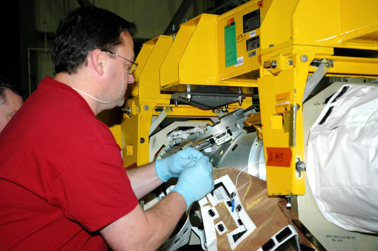 KENNEDY SPACE CENTER, FLA.  - In the back transfer aisle of the Orbiter Processing Facility bay 3, Todd Dugan, a technician with United Space Alliance, begins attaching the Thermal Protection System (TPS) blanket to the Orbiter Boom Sensor System (OBSS).  The installation of the insulation concludes TPS closeout prior to installation of the boom in the orbiter Discovery.  The OBSS is one of the new safety measures for Return to Flight, equipping the Shuttle with cameras and laser systems to inspect the Shuttle’s Thermal Protection System while in space.  Discovery is designated as the Return to Flight vehicle for mission STS-114, with a launch window of May 12 to June 3, 2005.