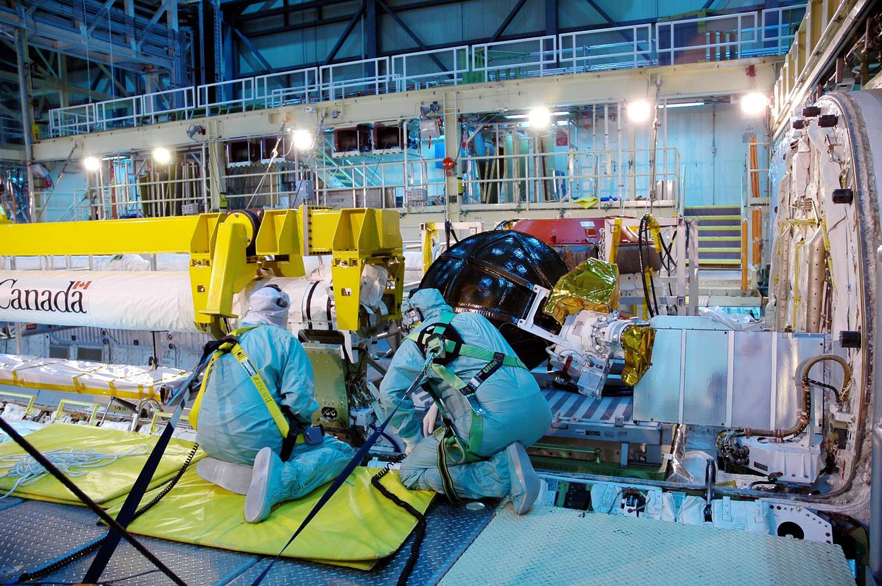 KENNEDY SPACE CENTER, FLA.  - In the Orbiter Processing Facility bay 3, workers install the Orbiter Boom Sensor System (OBSS) onto the starboard side of Discovery’s payload bay.    The 50-foot-long OBSS attaches to the Remote Manipulator System, or Shuttle robotic arm, and is one of the new safety measures for Return to Flight, equipping the orbiter with cameras and laser systems to inspect the Shuttle’s Thermal Protection System while in space.  The Return to Flight mission, STS-114,  has a launch window of May 12 to June 3, 2005.
