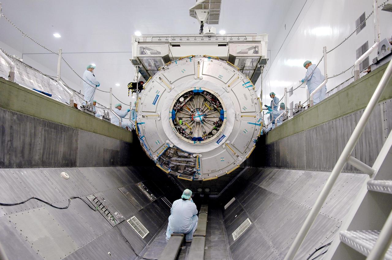 KENNEDY SPACE CENTER, FLA.  - In the Space Station Processing Facility, technicians stand by as the International Space Station module Node 2 is lowered into a payload canister.  The module is being transferred to the Operations and Checkout Building where it will undergo an element leak test.  The installation of NASA's Node 2 will denote the U.S. Core Complete stage of International Space Station assembly and increase the living and working space inside the station to approximately 18,000 cubic feet. It also will allow the addition of international laboratories from Europe and Japan to the station.  Node 2 will provide a passageway between four station science experiment facilities: the U.S. Destiny Laboratory, the Kibo Japanese Experiment Module, the European Columbus Laboratory and the Centrifuge Accommodation Module. It also will provide connecting ports for Multi-Purpose Logistics Modules, the Japanese H II Transfer Vehicle and the Pressurized Mating Adapter 2 to which Space Shuttles dock. The Space Station Robotic Arm, Canadarm2, can operate from a powered grapple fixture on the exterior of Node 2.  It is scheduled for launch on shuttle mission STS-120, station assembly flight 10A.