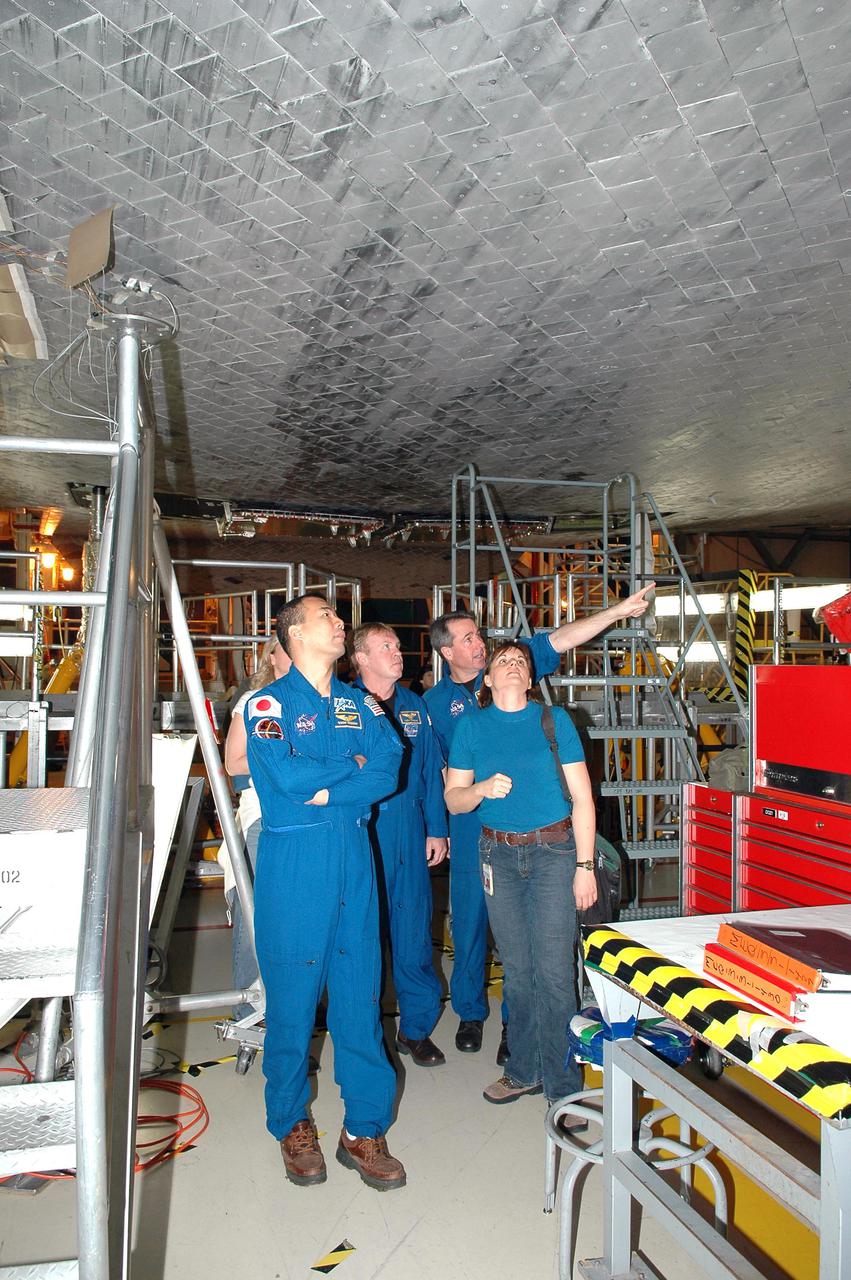 KENNEDY SPACE CENTER, FLA.  - In the Orbiter Processing Facility, members of the STS-114 crew look at Discovery, the orbiter designated for the Return to Flight mission.  From left are Mission Specialists Soichi Noguchi (with the Japanese Space Agency), Andrew Thomas and Stephen Robinson.  They and other crew members are at KSC for Crew Equipment Interface Test activities. During CEIT, the crew has an opportunity to get a hands-on look at the orbiter and equipment they will be working with on the mission.  Return to Flight Mission STS-114 will carry the Multi-Purpose Logistics Module Raffaello, filled with supplies for the International Space Station, and a replacement Control Moment Gyroscope.  Launch of STS-114 has a launch window of May 12 to June 3.