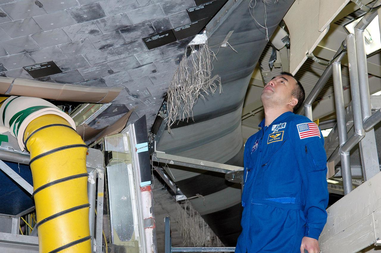 KENNEDY SPACE CENTER, FLA. - In the Orbiter Processing Facility, STS-114 Mission Specialist Soichi Noguchi (with the Japanese Space Agency) looks closely at the Reinforced Carbon-Carbon panel on Discovery’s wing leading edge. The panels are part of the Thermal Protection System on the orbiter. Noguchi and other crew members are at KSC for Crew Equipment Interface Test activities. During CEIT, the crew has an opportunity to get a hands-on look at the orbiter and equipment they will be working with on the mission. Return to Flight Mission STS-114 will carry the Multi-Purpose Logistics Module Raffaello, filled with supplies for the International Space Station, and a replacement Control Moment Gyroscope. Launch of STS-114 has a launch window of May 12 to June 3.