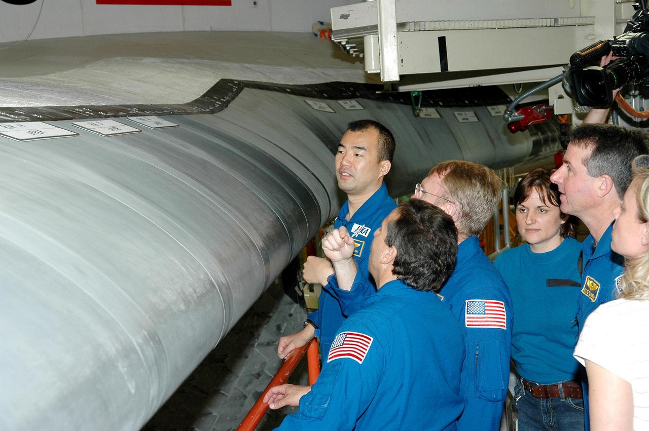 KENNEDY SPACE CENTER, FLA. - In the Orbiter Processing Facility, members of the STS-114 crew take a close look at the Reinforced Carbon-Carbon on the wing’s leading edge on Discovery. From left are Mission Specialists Soichi Noguchi (with the Japanese Space Agency), Charles Camarda and Andrew Thomas; accompanied by Cindy Begley, lead EVA flight controller. At right is Mission Specialist Stephen Robinson, with Christi Hansen, EVA trainer. The crew is at KSC for Crew Equipment Interface Test activities. The leading edge panels of the orbiters’ wings have 22 Reinforced Carbon-Carbon panels, made entirely of carbon composite material. The molded components are approximately 0.25-inch to 0.5-inch thick. During CEIT, the crew has an opportunity to get a hands-on look at the orbiter and equipment they will be working with on the mission. Return to Flight Mission STS-114 will carry the Multi-Purpose Logistics Module Raffaello, filled with supplies for the International Space Station, and a replacement Control Moment Gyroscope. Launch of STS-114 has a launch window of May 12 to June 3.