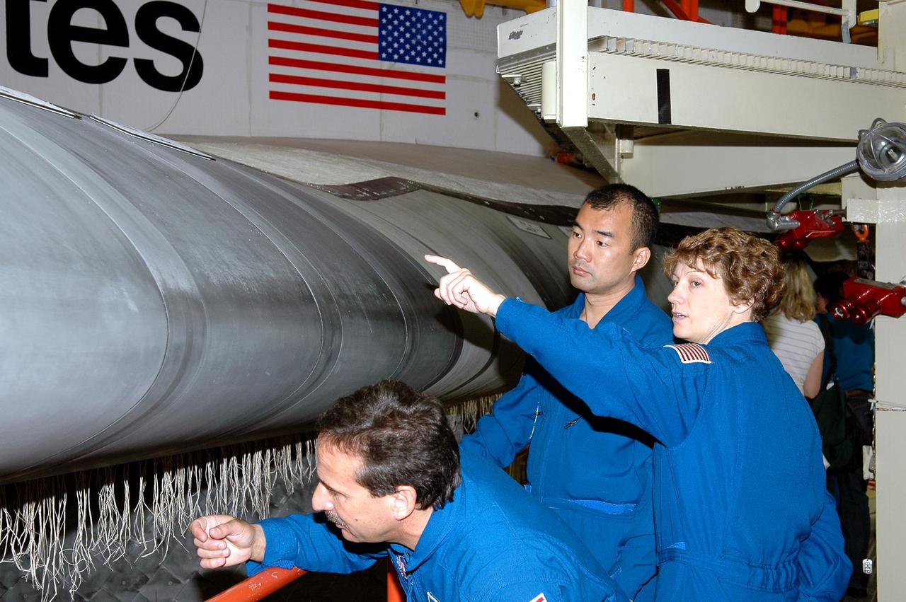 KENNEDY SPACE CENTER, FLA.  - In the Orbiter Processing Facility, members of the STS-114 crew take a close look at the Reinforced Carbon-Carbon on the wing’s leading edge on Discovery.  From left are Mission Specialists Charles Camarda and Soichi Noguchi (with the Japanese Space Agency), and Commander Eileen Collins.  They and other crew members are at KSC for Crew Equipment Interface Test activities. The leading edge panels of the orbiters’ wings have 22 RCC panels, made entirely of carbon composite material. The molded components are approximately 0.25-inch to 0.5-inch thick. The leading edge panels of the orbiters’ wings have 22 Reinforced Carbon-Carbon panels, made entirely of carbon composite material. The molded components are approximately 0.25-inch to 0.5-inch thick. During CEIT, the crew has an opportunity to get a hands-on look at the orbiter and equipment they will be working with on the mission.  Return to Flight Mission STS-114 will carry the Multi-Purpose Logistics Module Raffaello, filled with supplies for the International Space Station, and a replacement Control Moment Gyroscope.  Launch of STS-114 has a launch window of May 12 to June 3.